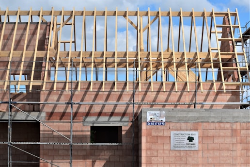 Building under construction with wooden roof trusses.