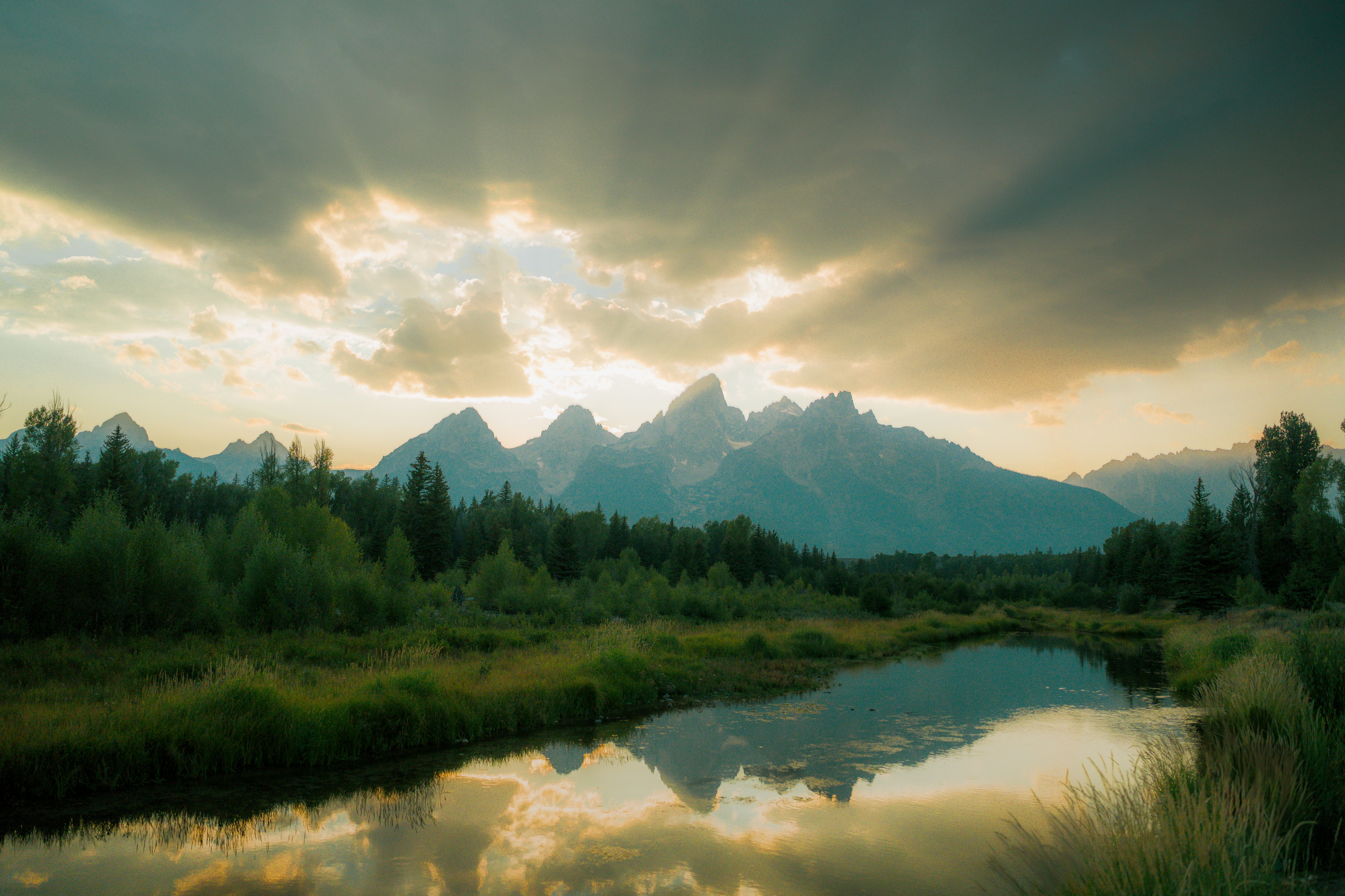 Sunbeams break through clouds over mountains and reflection.