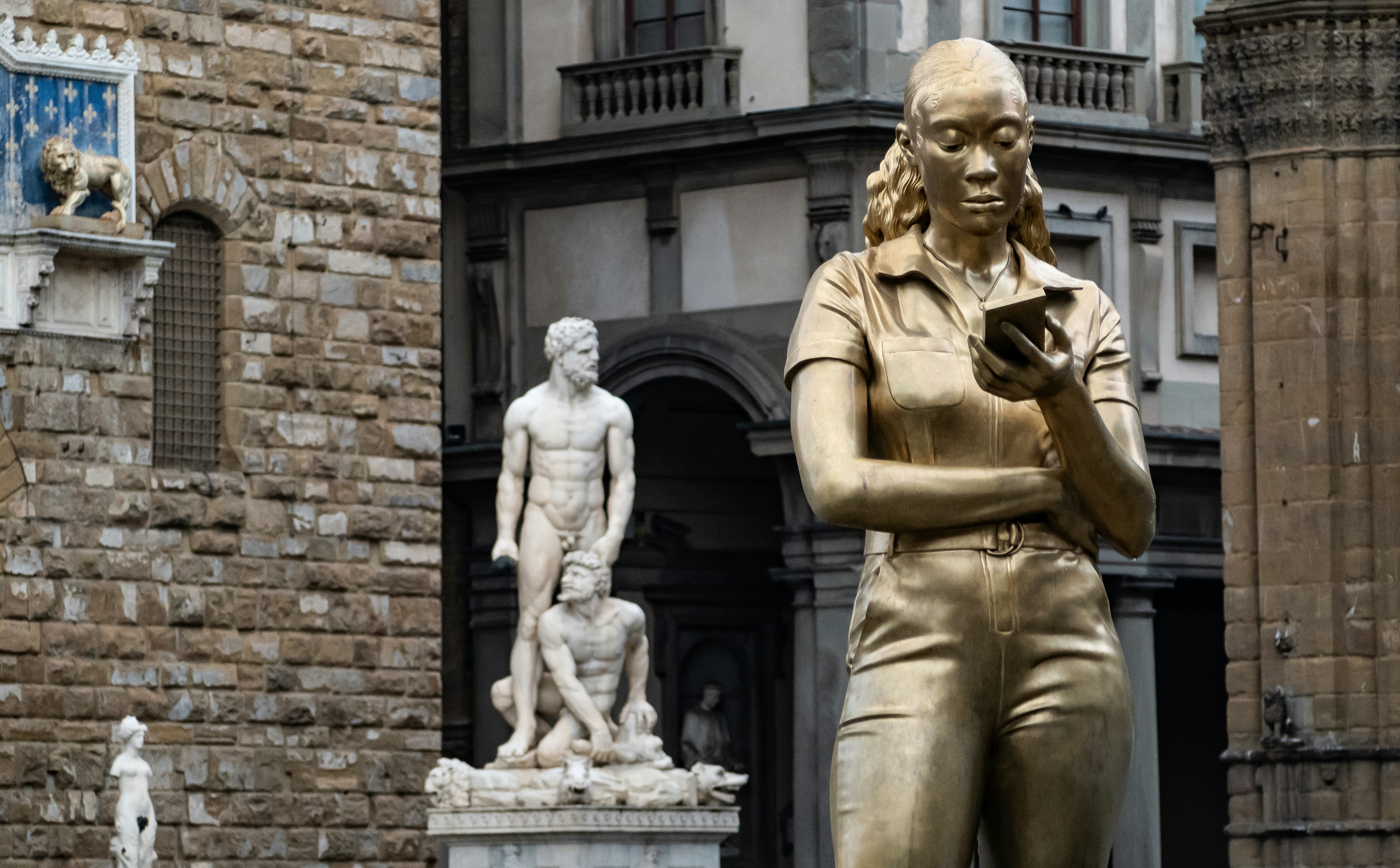 Golden statue of woman looking at phone