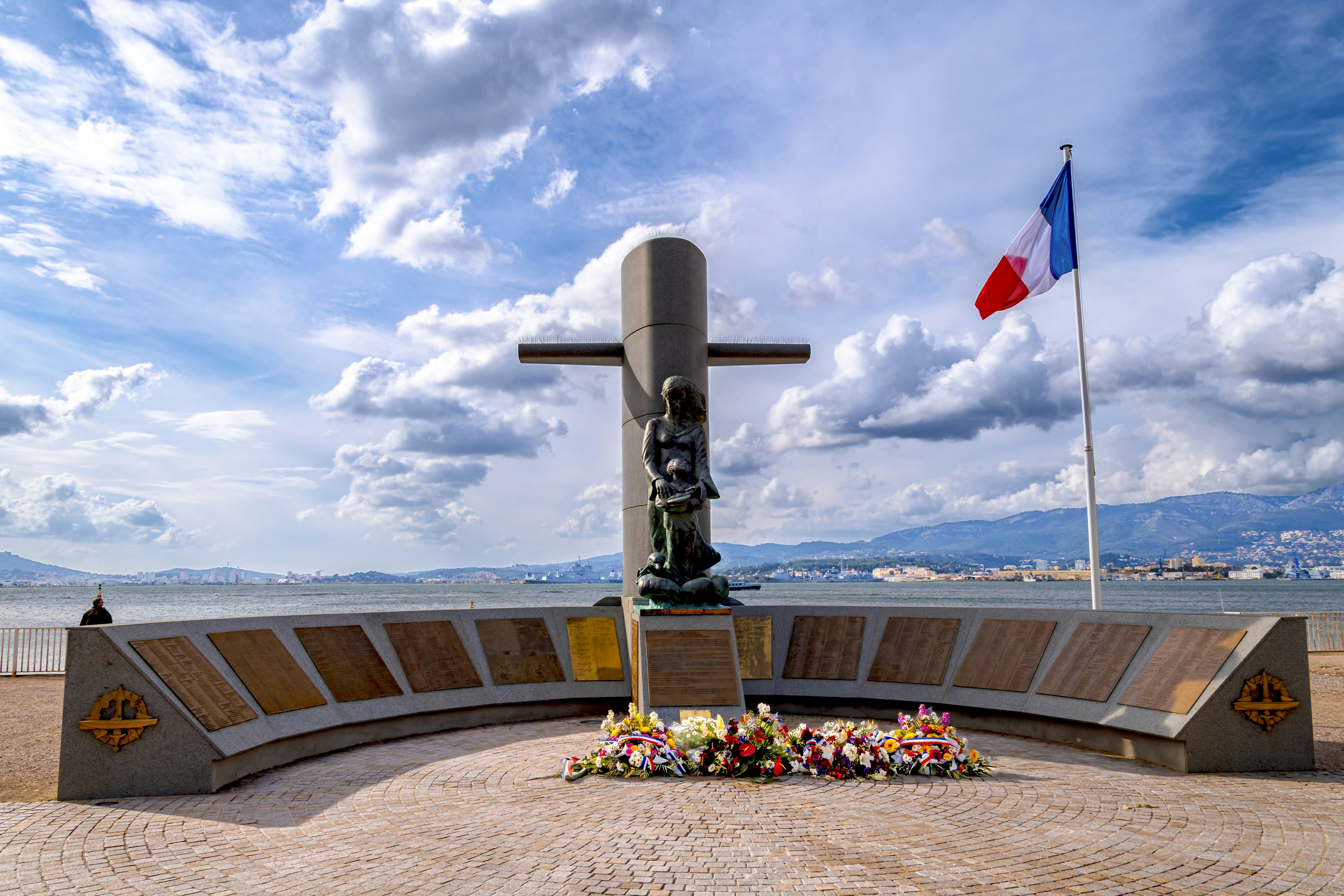 Monument with french flag and floral tribute by sea