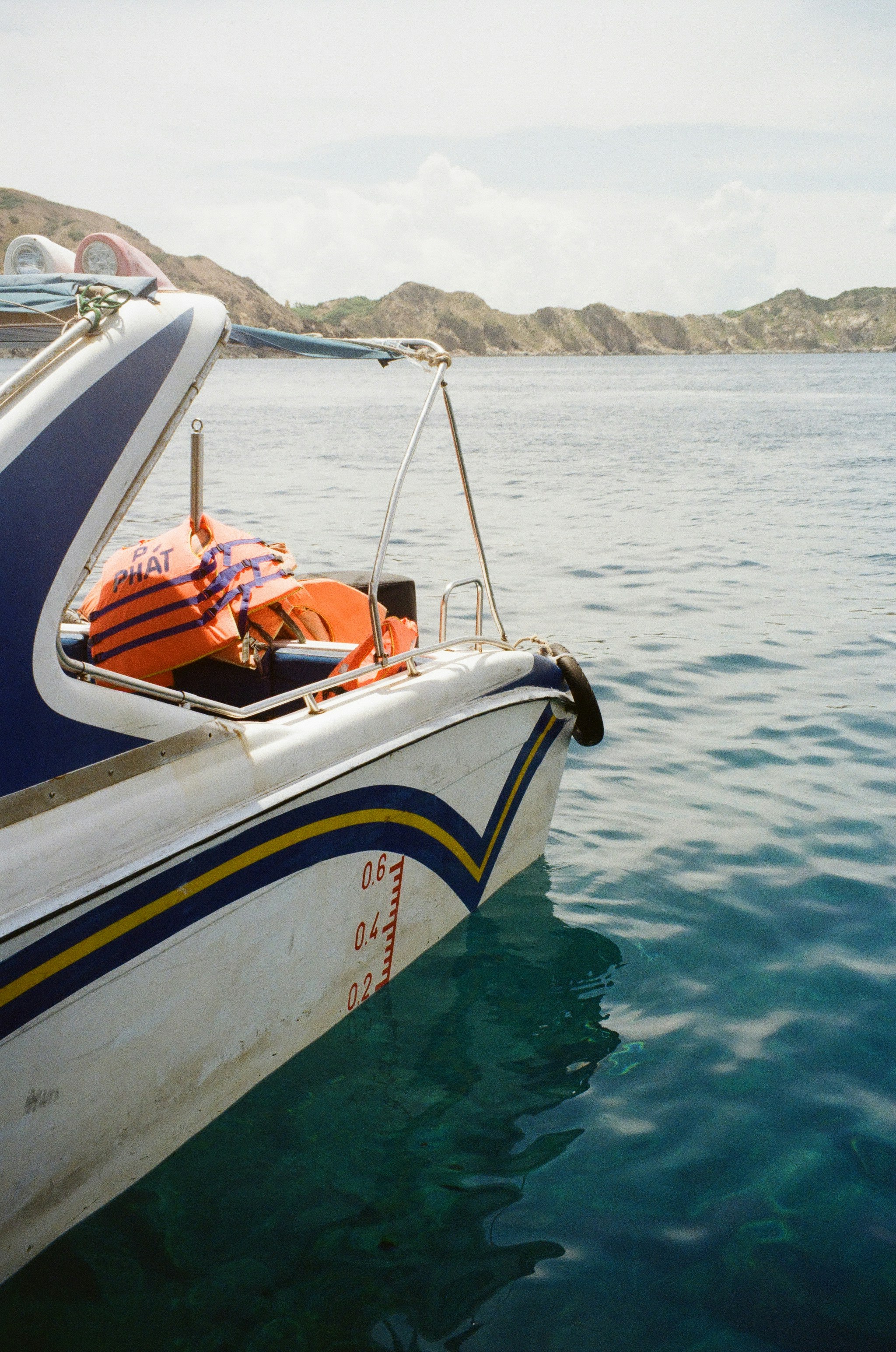 Boat with life vests moored in clear blue water.
