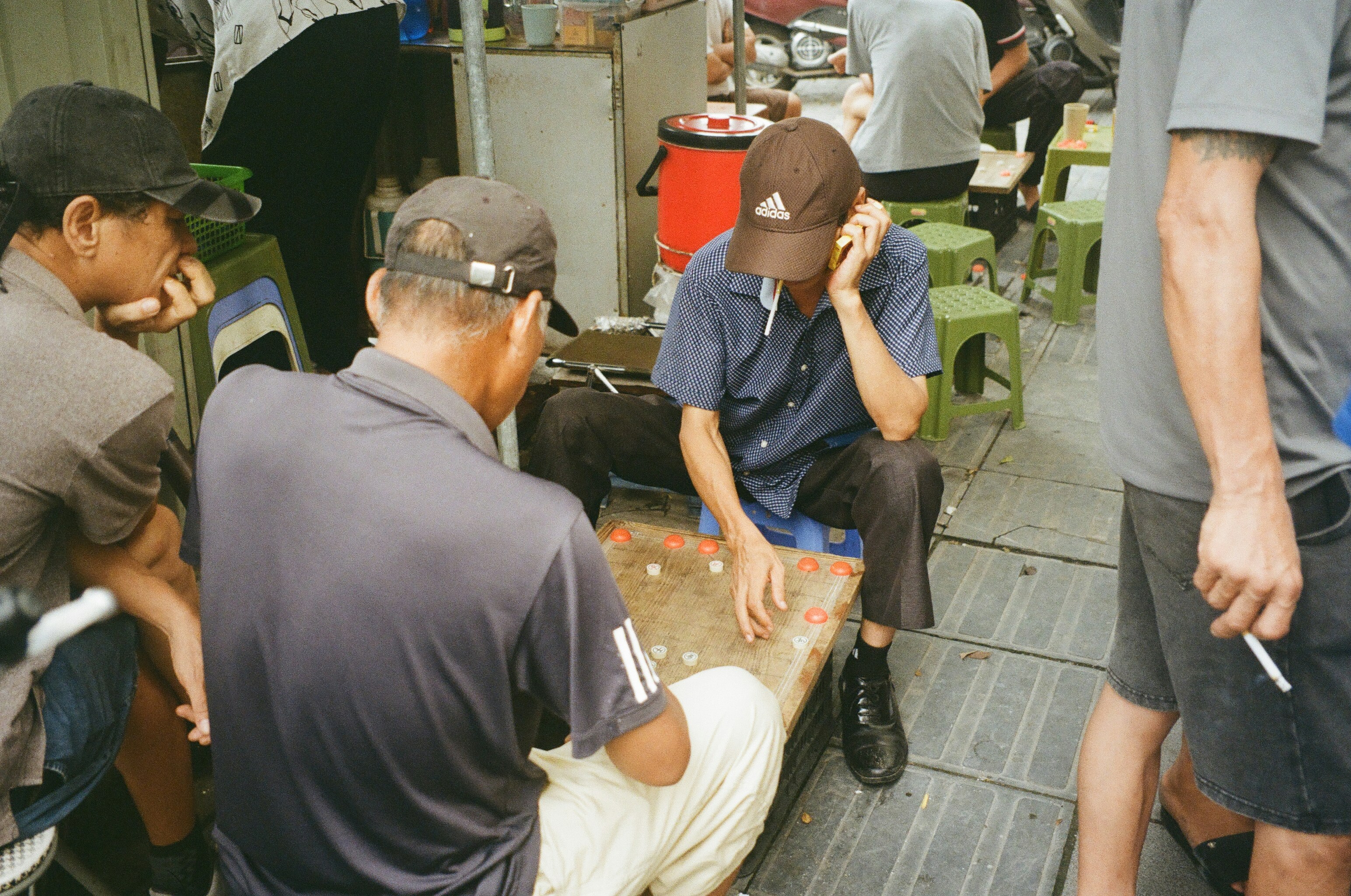 Men playing a board game outdoors on the street.