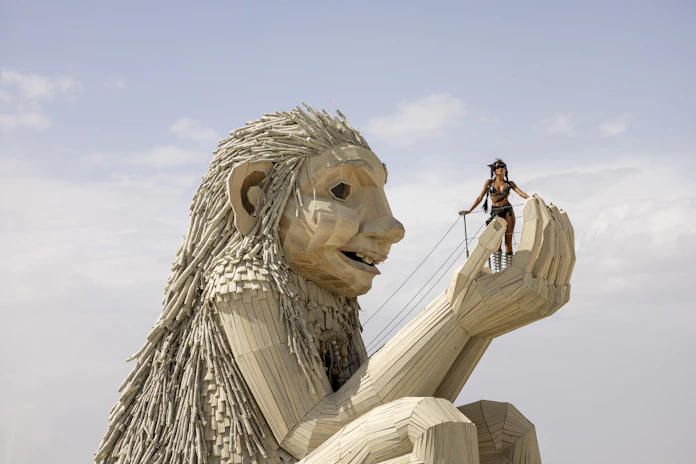 Giant wooden sculpture with a small person playing harp