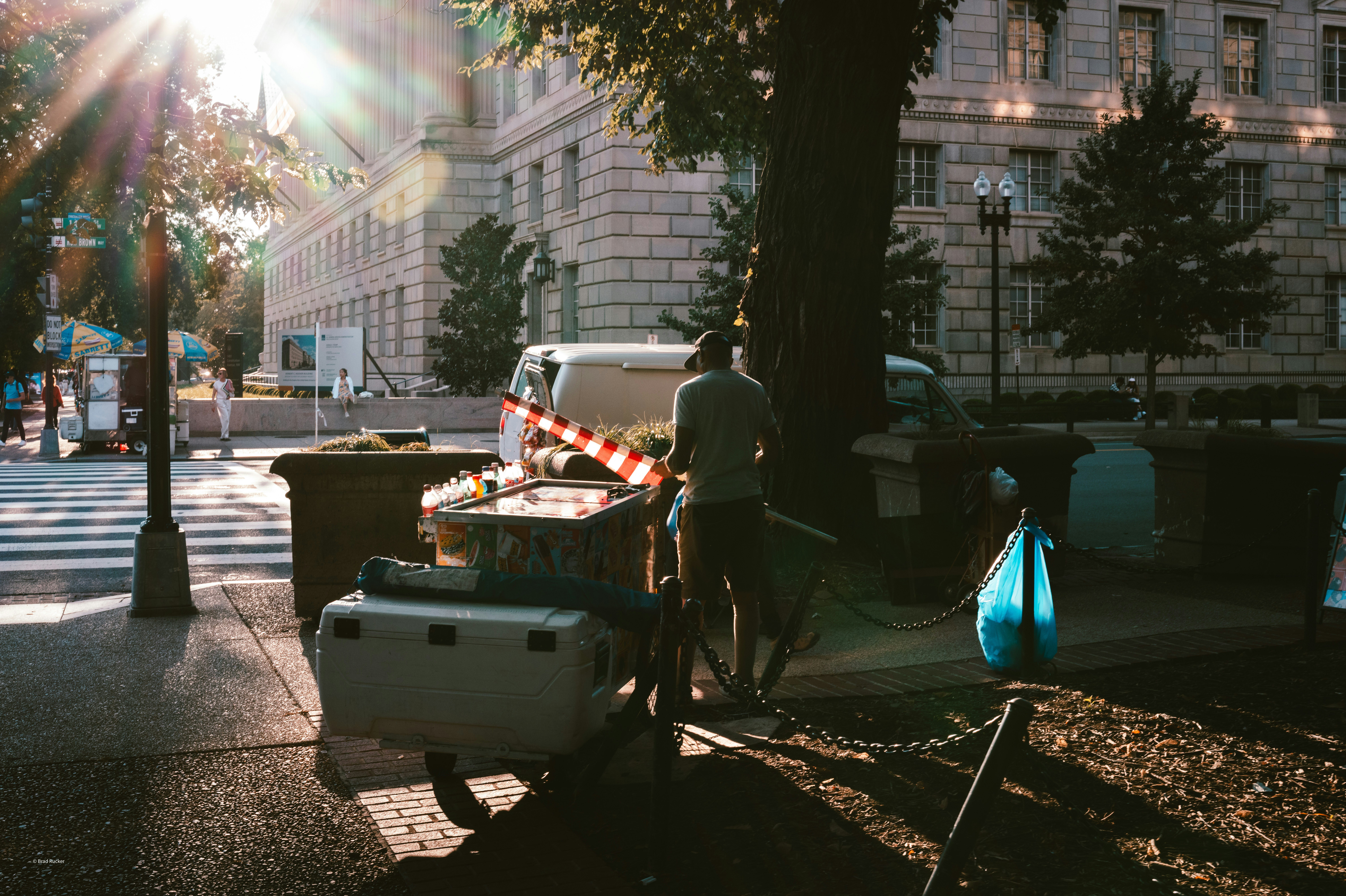 Person standing near a trailer on a sunny street.