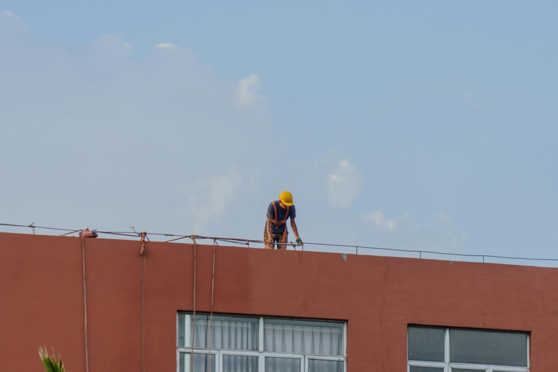 Worker in yellow hard hat on building roof