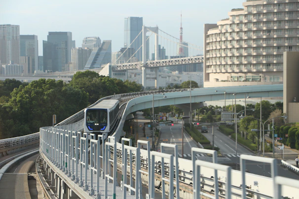 A train travels on an elevated track with city buildings.