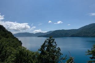A serene blue lake surrounded by lush green mountains.