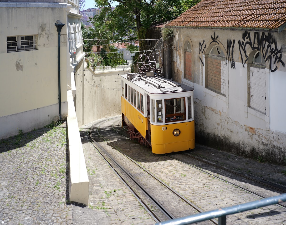 A yellow tram ascends a steep track between buildings.