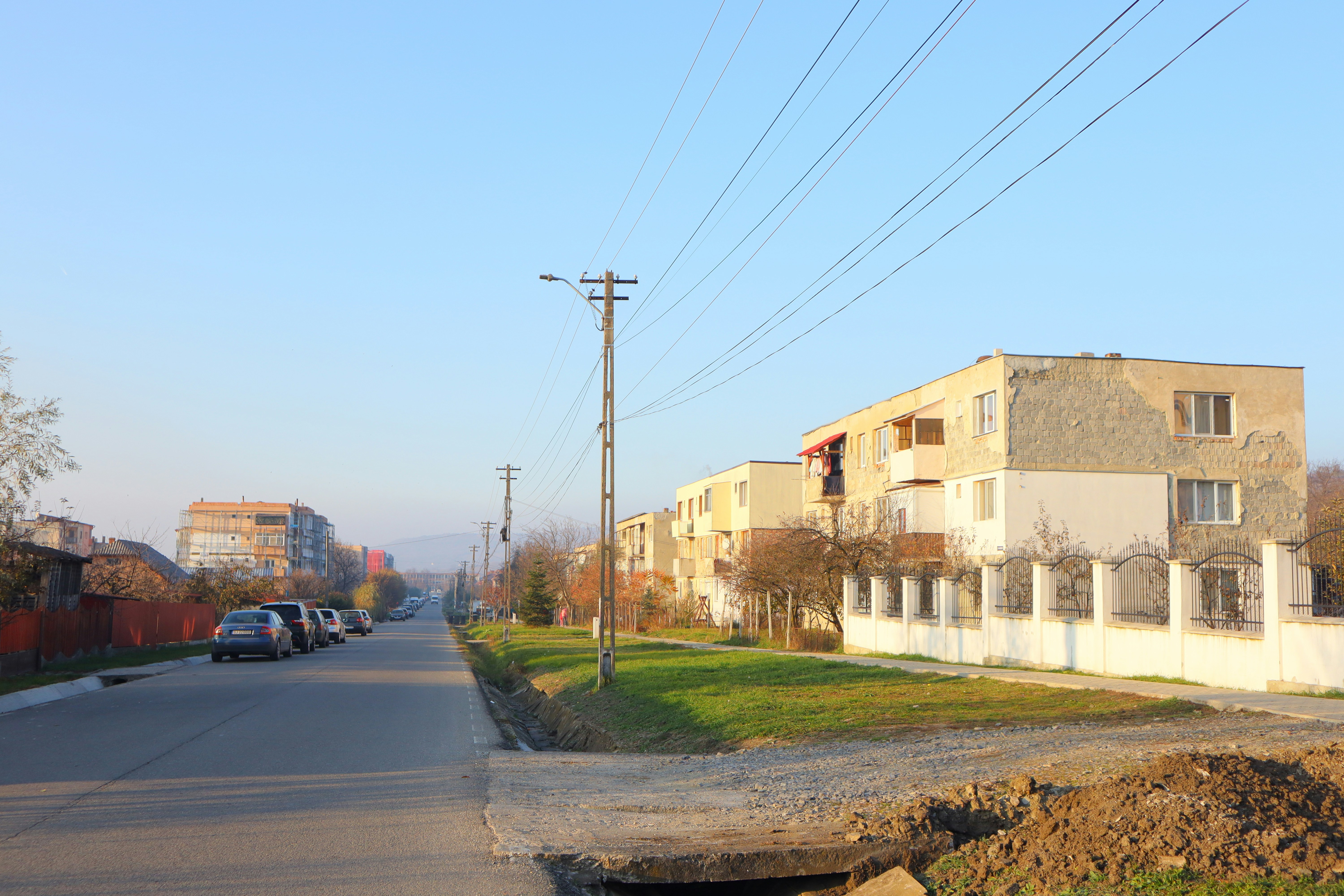 Street with apartment buildings and parked cars.