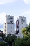 Two tall apartment buildings with trees in foreground.