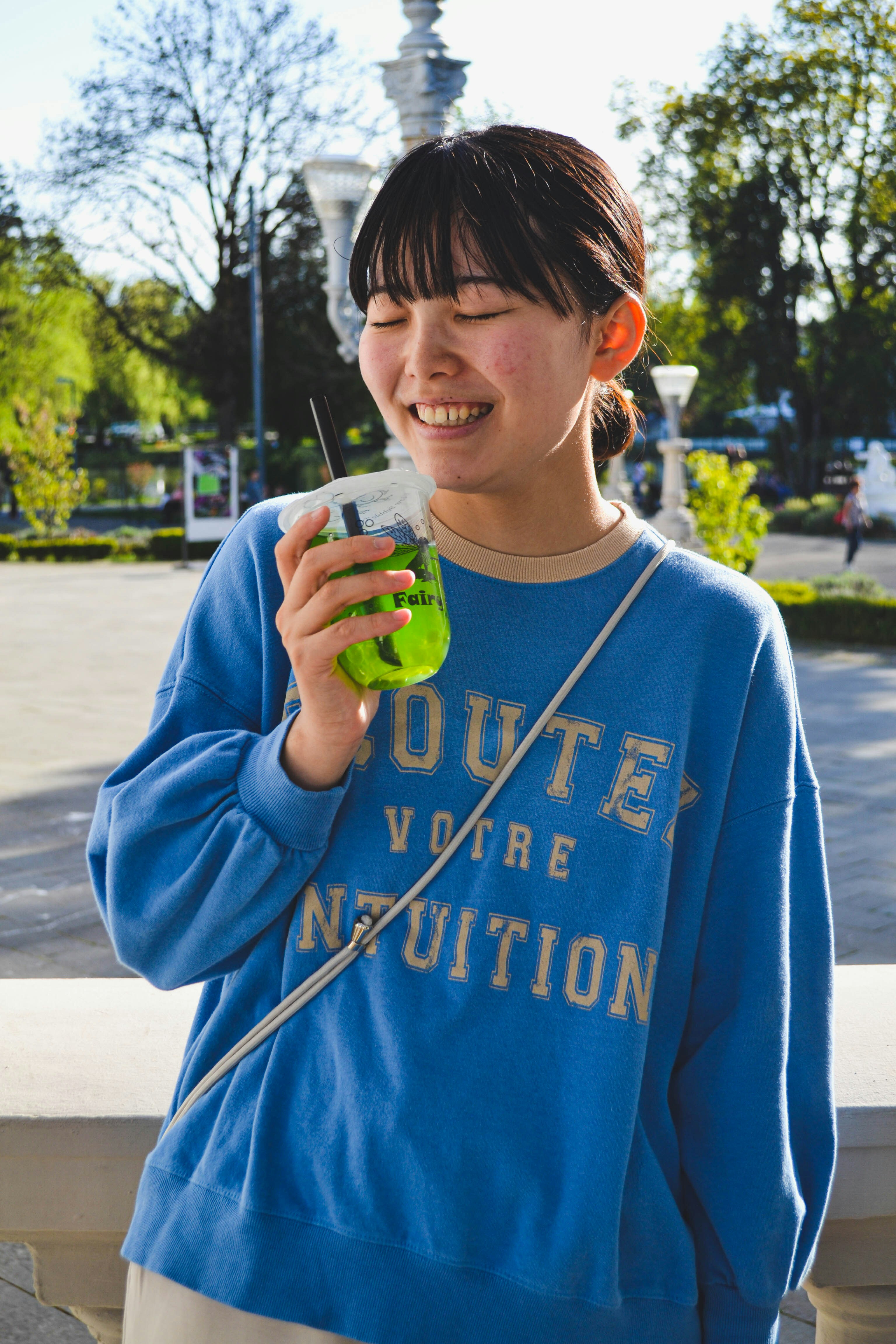 امرأة شابة تبتسم وهي تحمل مشروباً أخضر