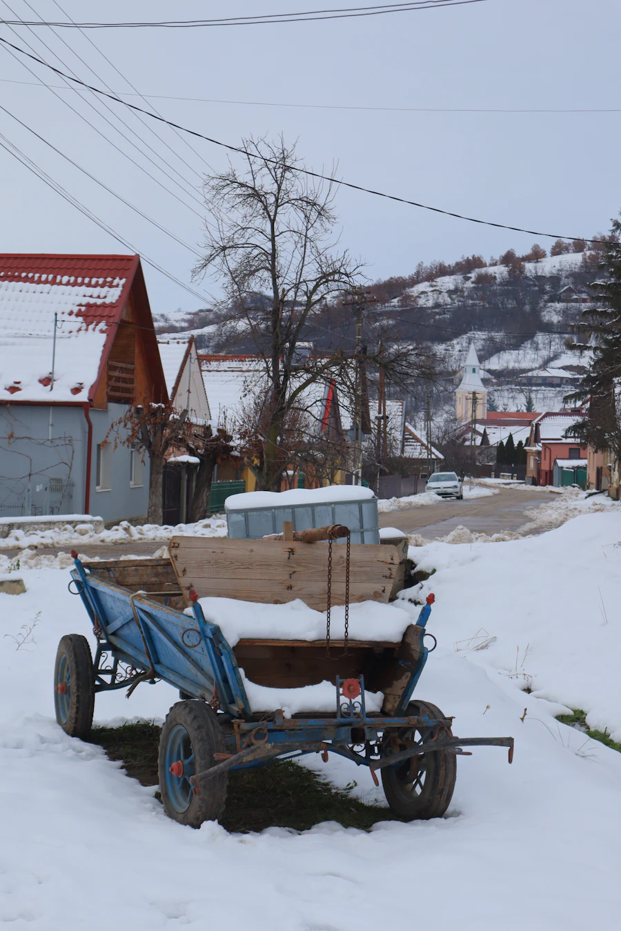 A blue wooden cart in the snow in a Romanian village