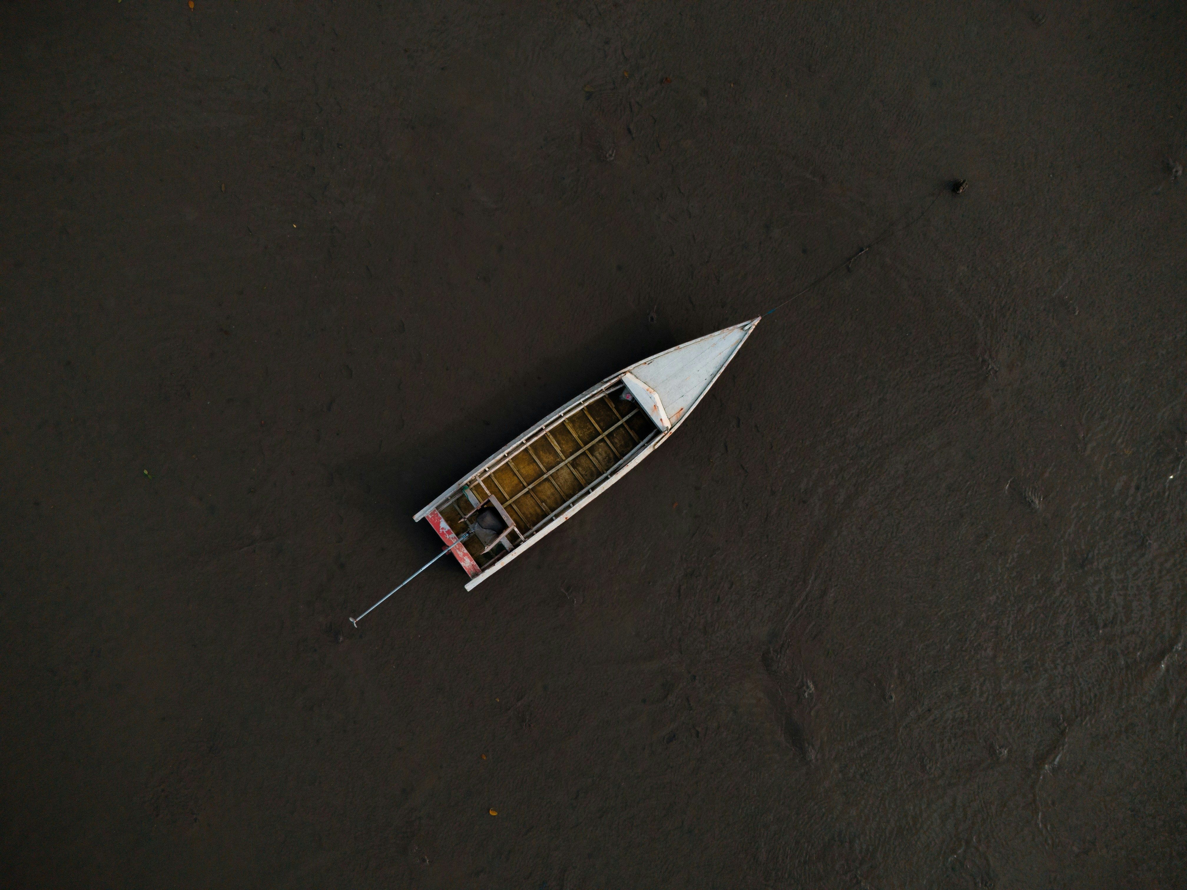 A small, white boat floats on dark water.