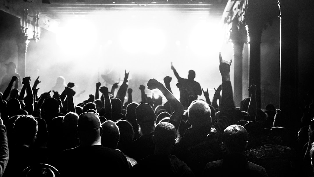 Concert crowd with hands raised at music festival with stage lights