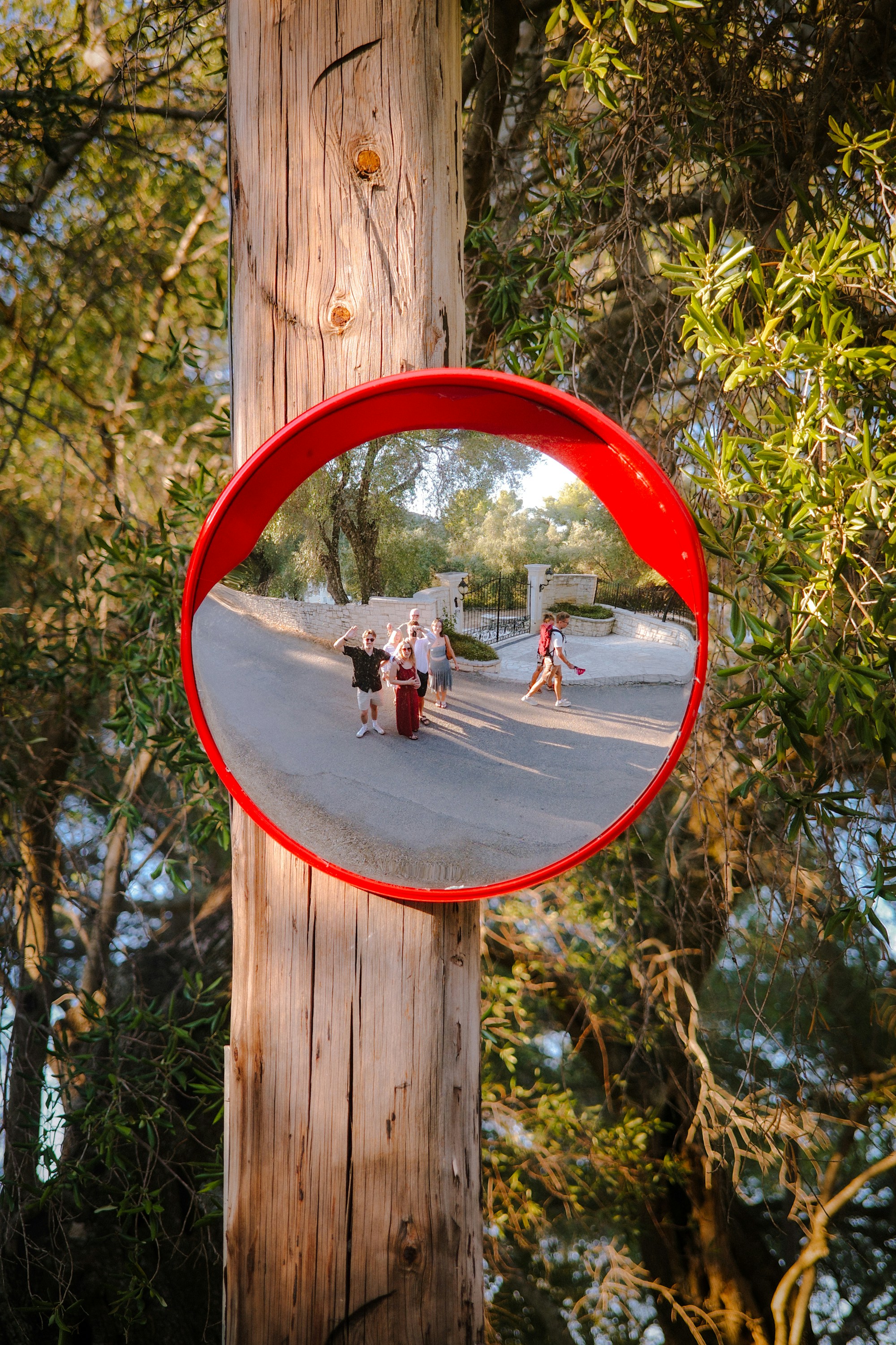 Convex mirror reflects people on a sunny road