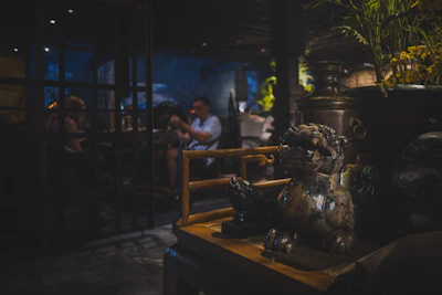 People dining in a dimly lit restaurant with decorative statues.