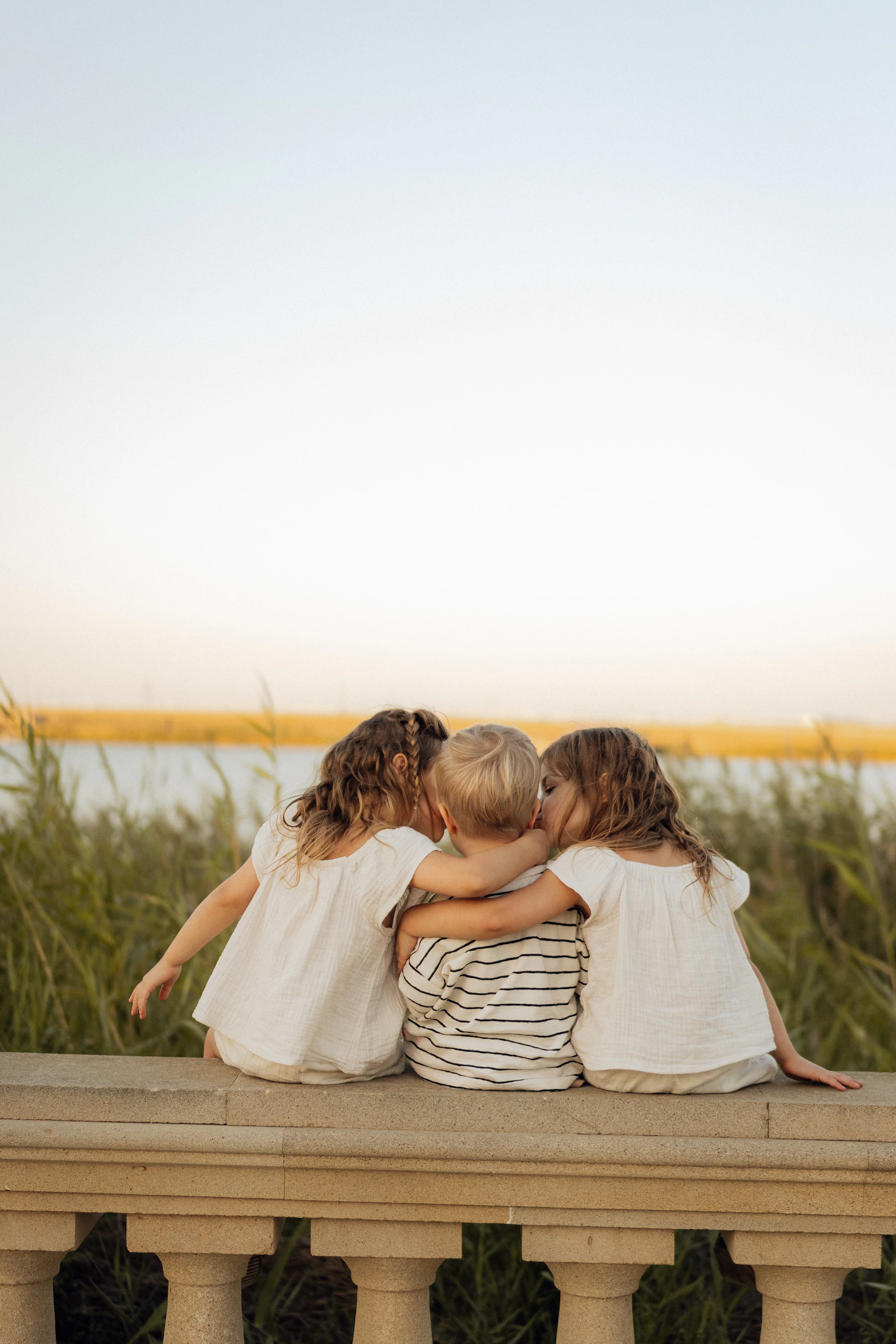 Three children embracing on a sunny day.