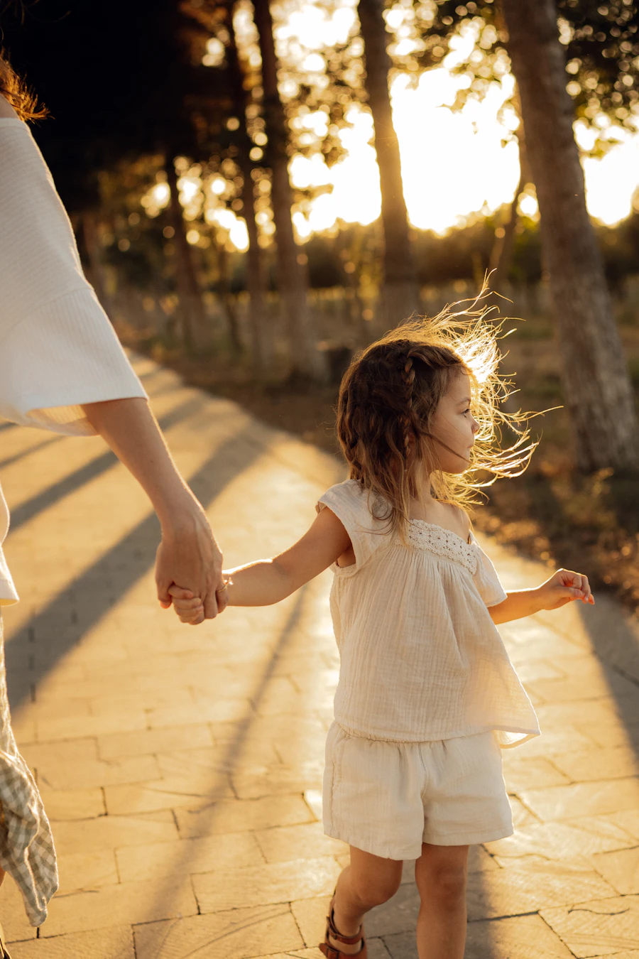 A child holding a parent's hand during a sunset walk