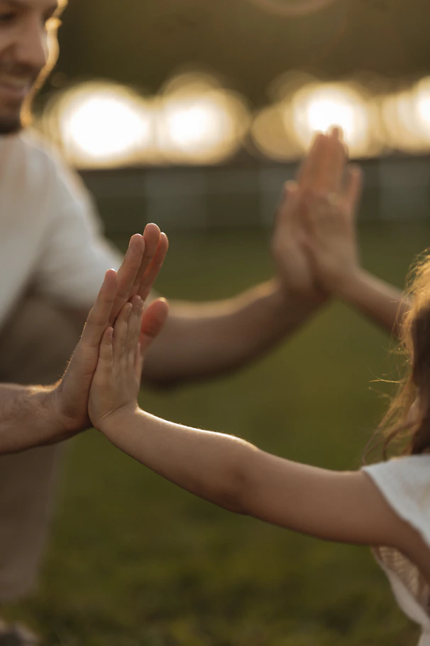 Father and child high-fiving outdoors at sunset