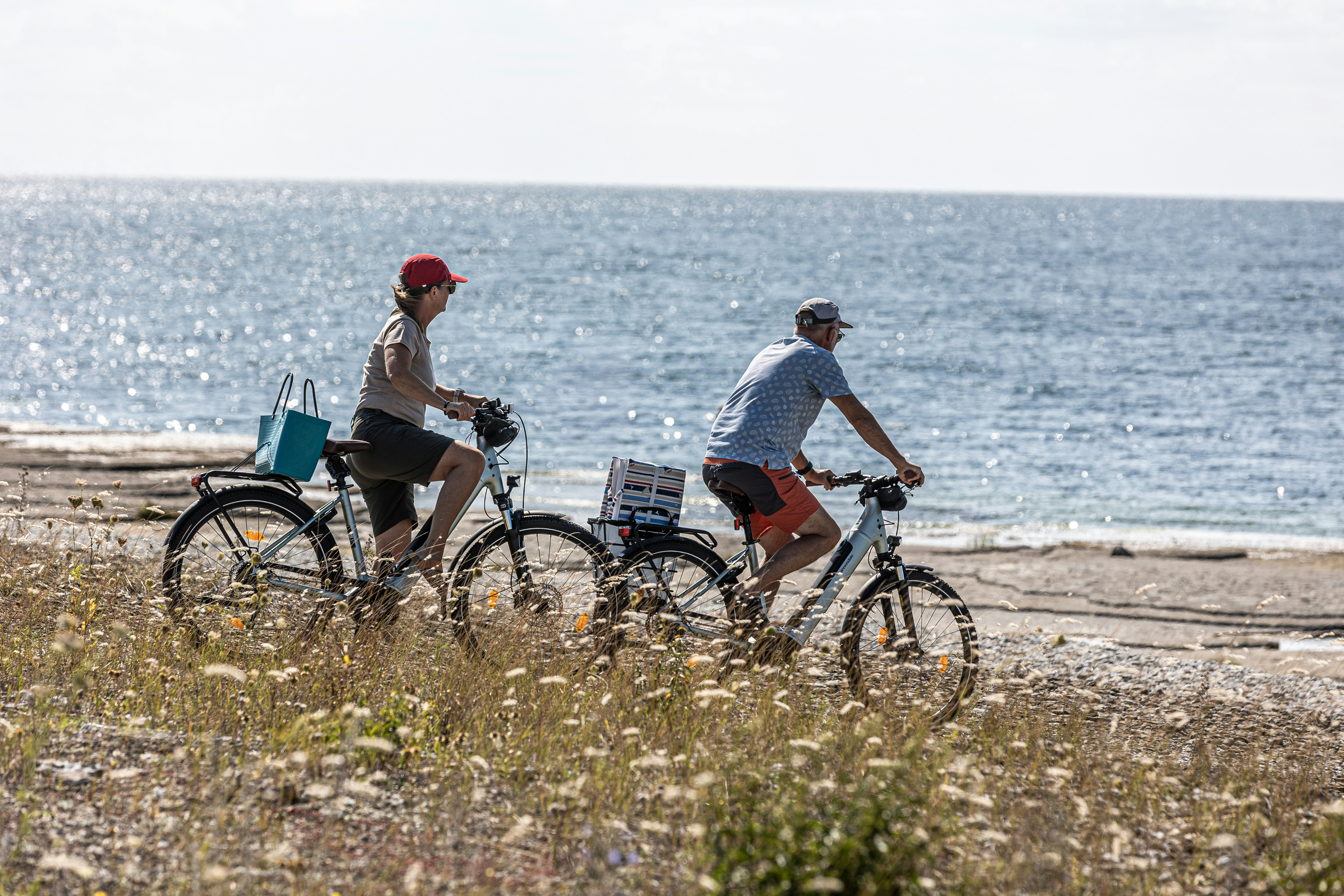 Two people riding bicycles along a beach path.