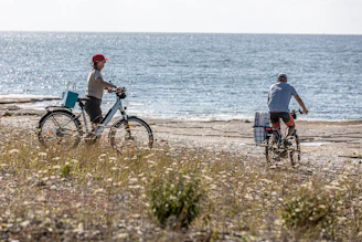 Two people cycling along the ocean shore.