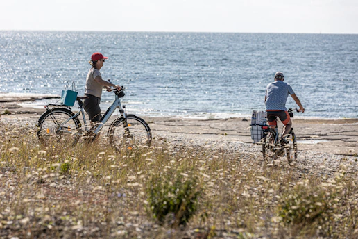 Two people cycling along the ocean shore.