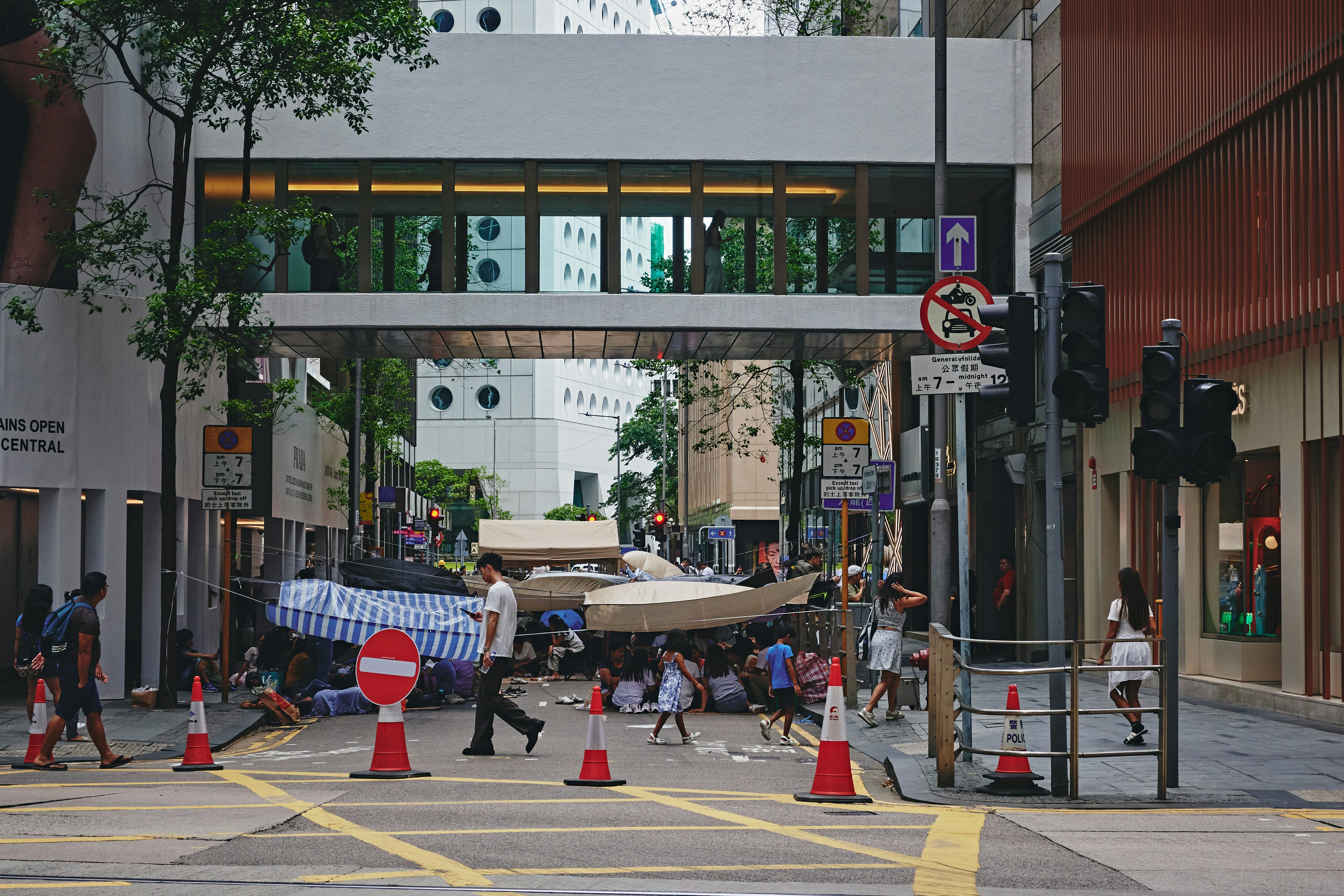 People gathered under makeshift shelter on city street.