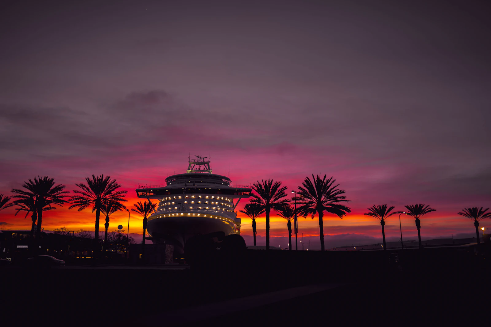 Cruise ship docked at a palm-lined port under a red and orange sunset, where an eSIM connects to local land networks