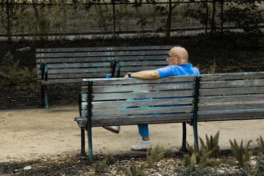 Man sits alone on a park bench.