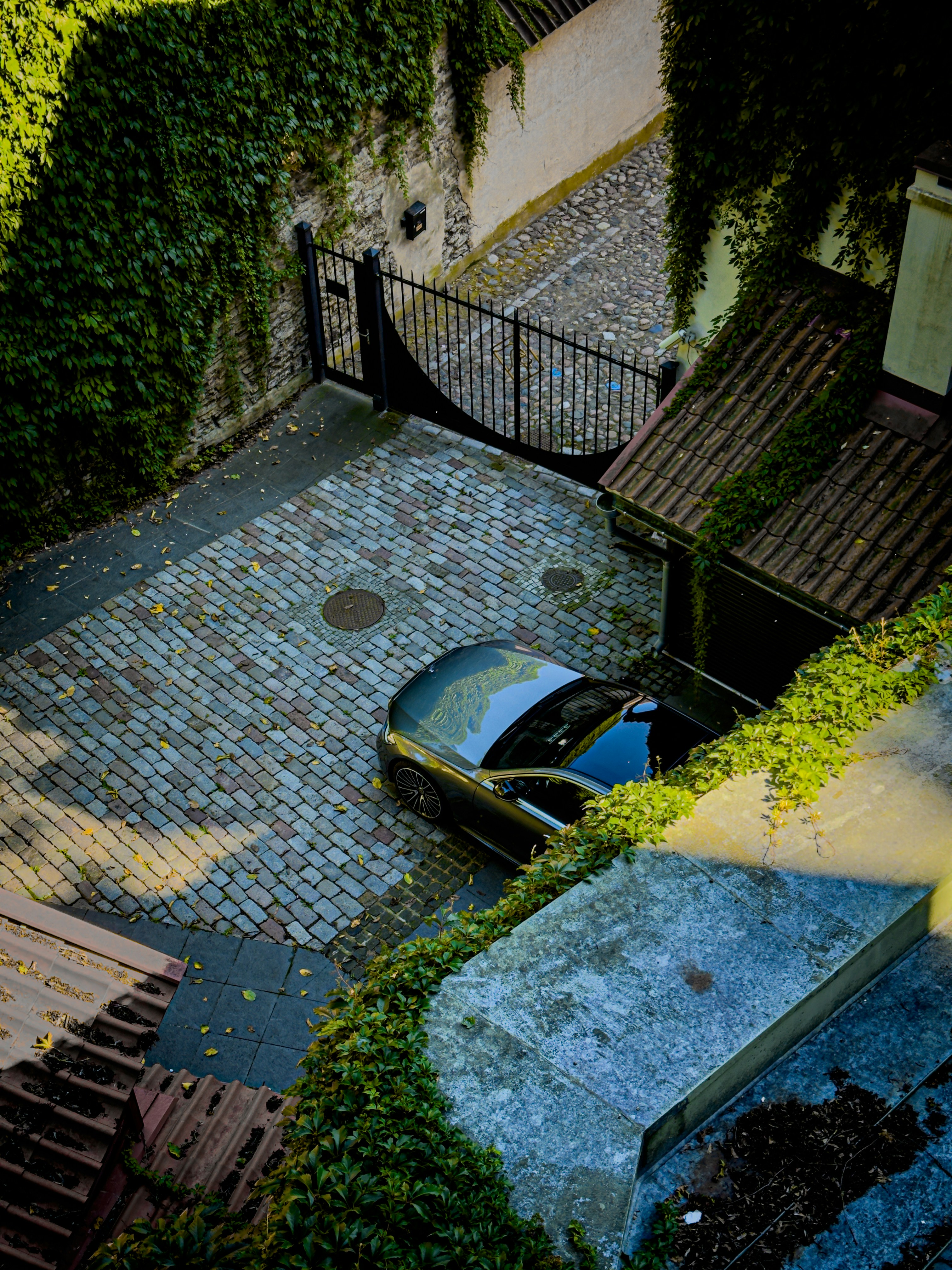 A black car parked in a cobblestone courtyard.