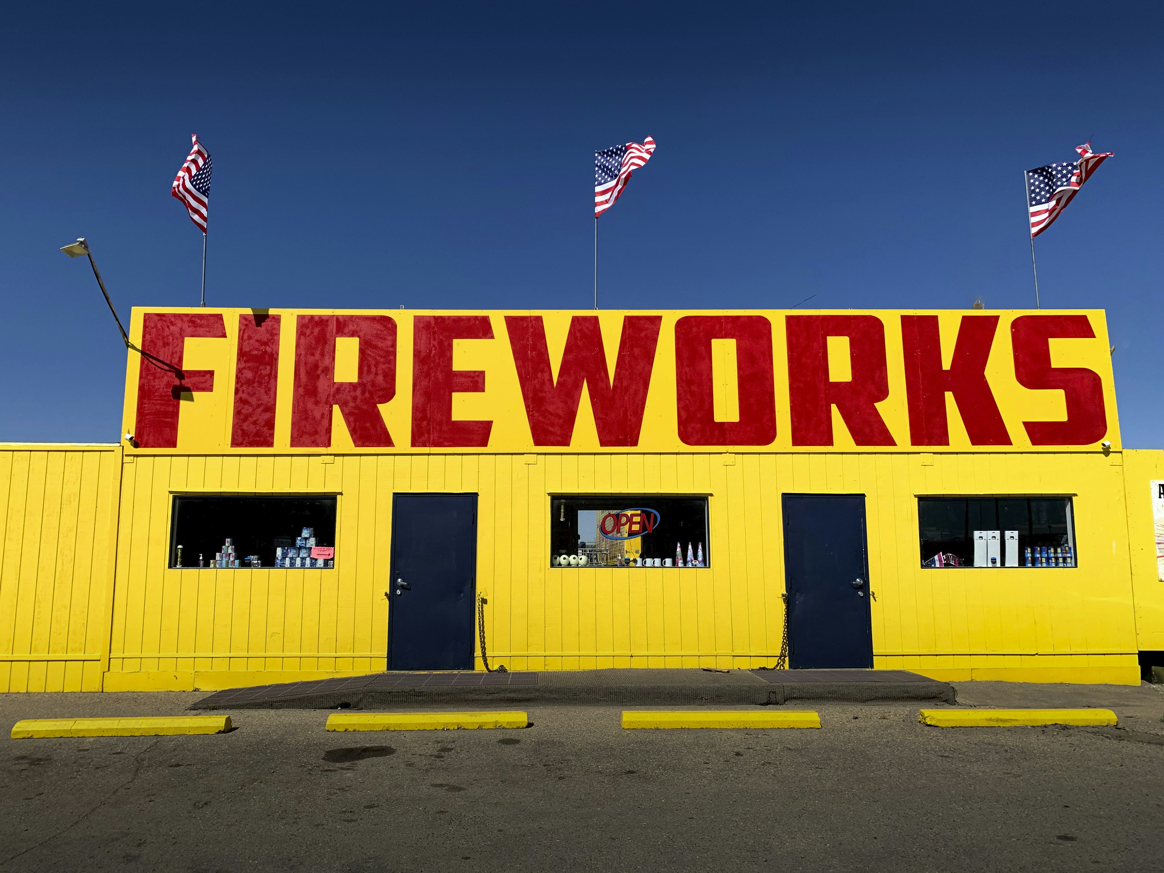 A bright yellow fireworks stand with american flags.