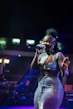 A woman sings into a microphone on stage.
