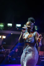 A woman sings into a microphone on stage.