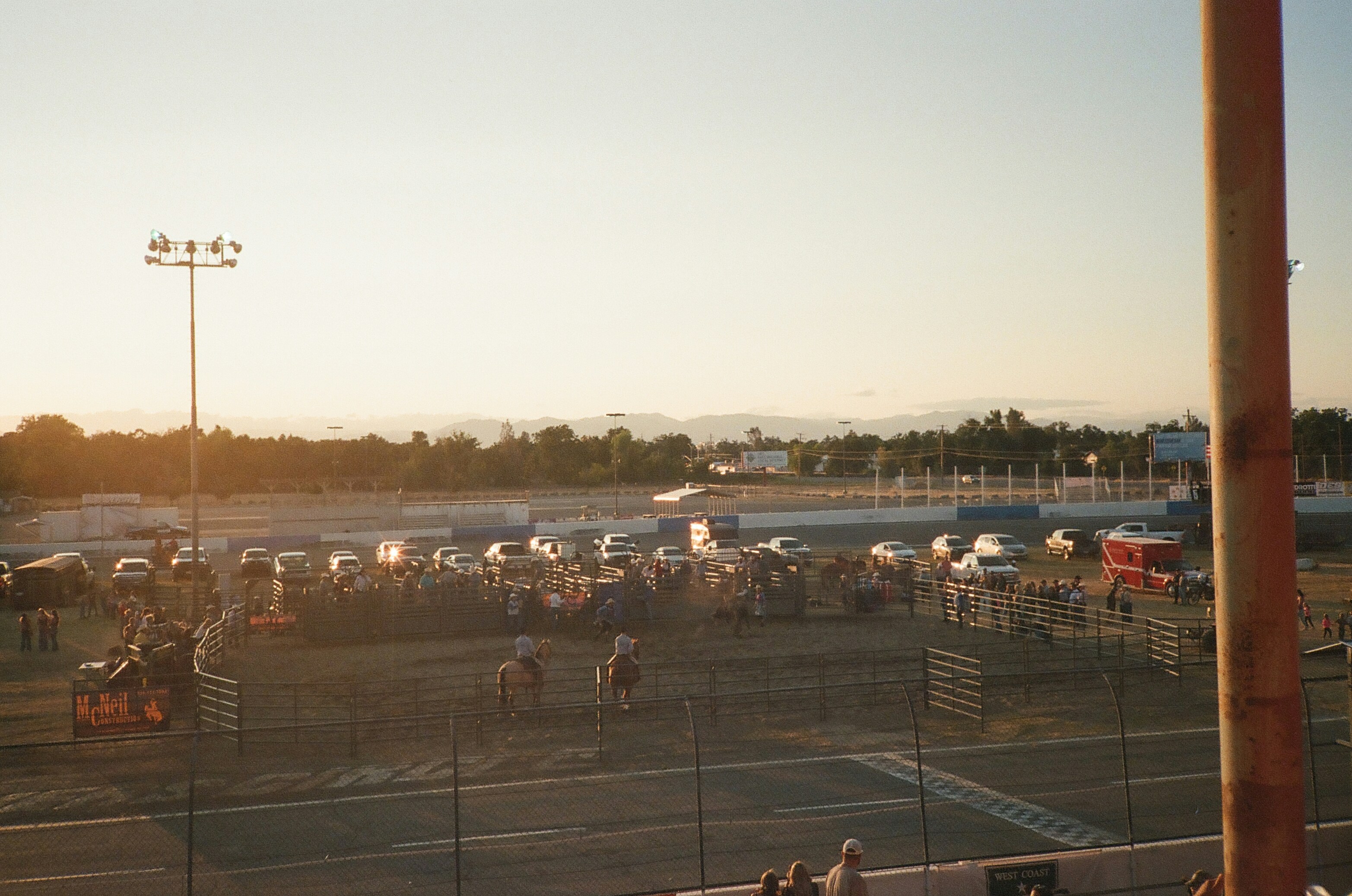 Rodeo event with spectators and horses at sunset