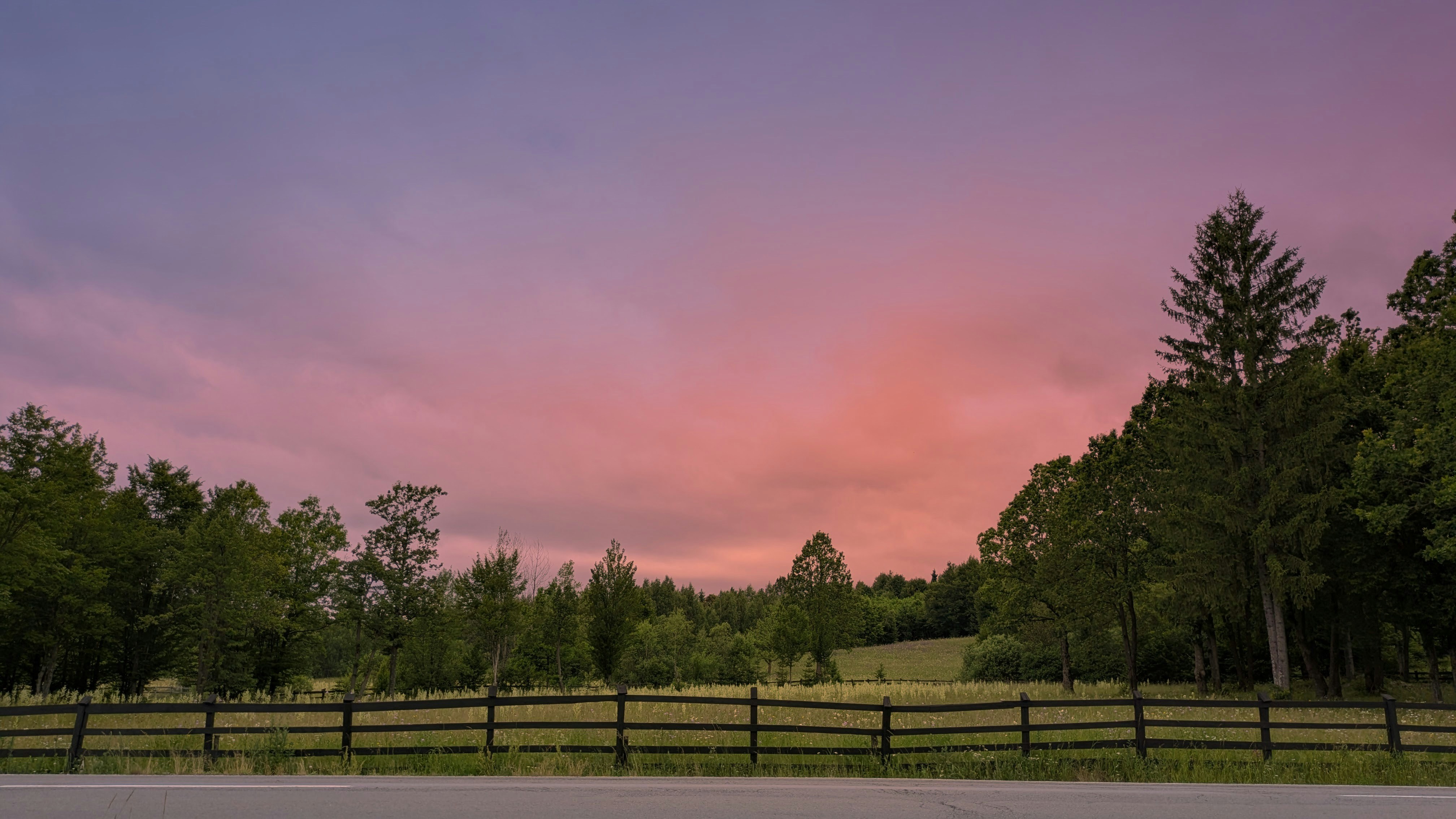Pastel sunset sky over a rural landscape with trees.