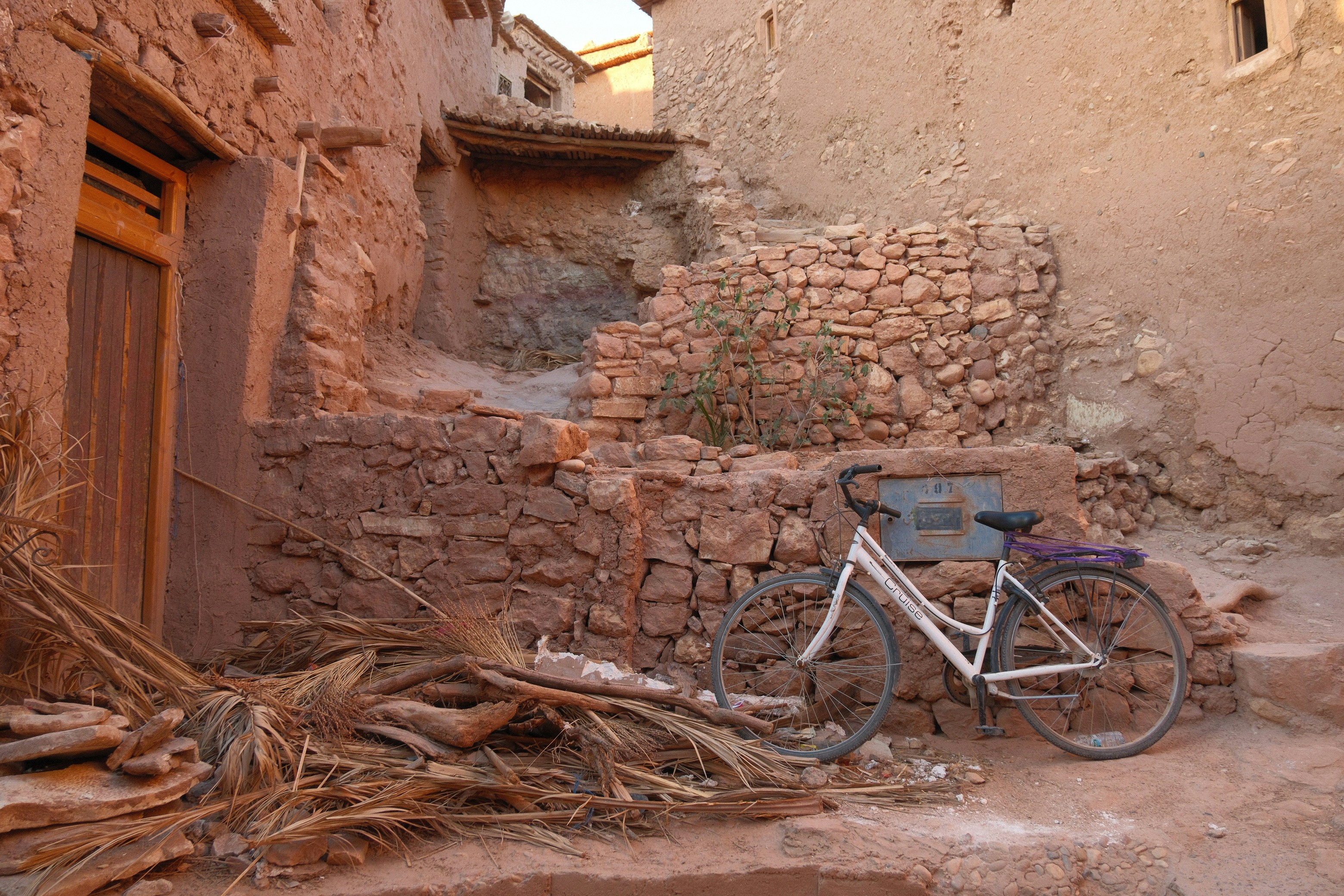 A white bicycle leans against a stone wall in a village.