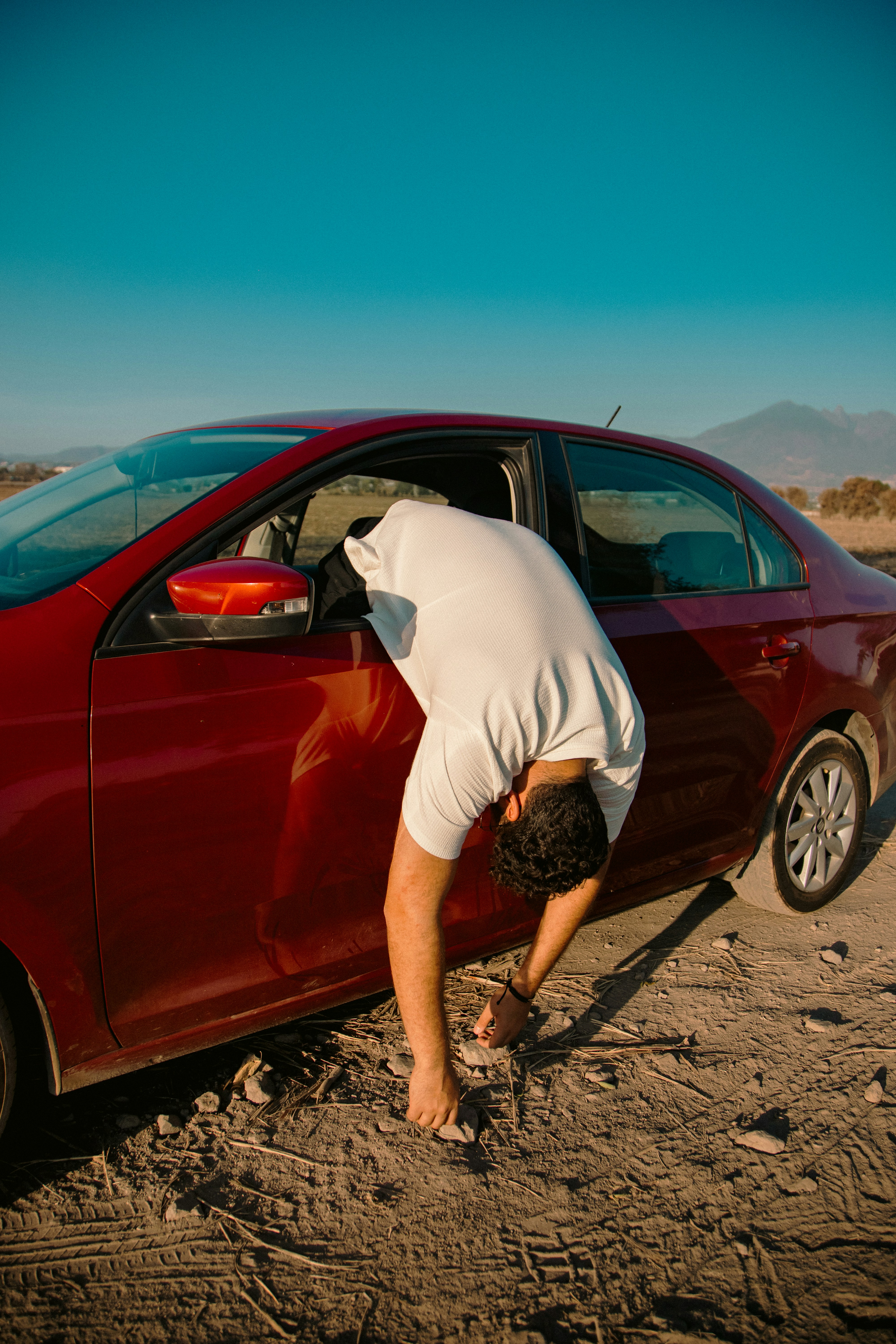 Man bending into car stuck in dirt