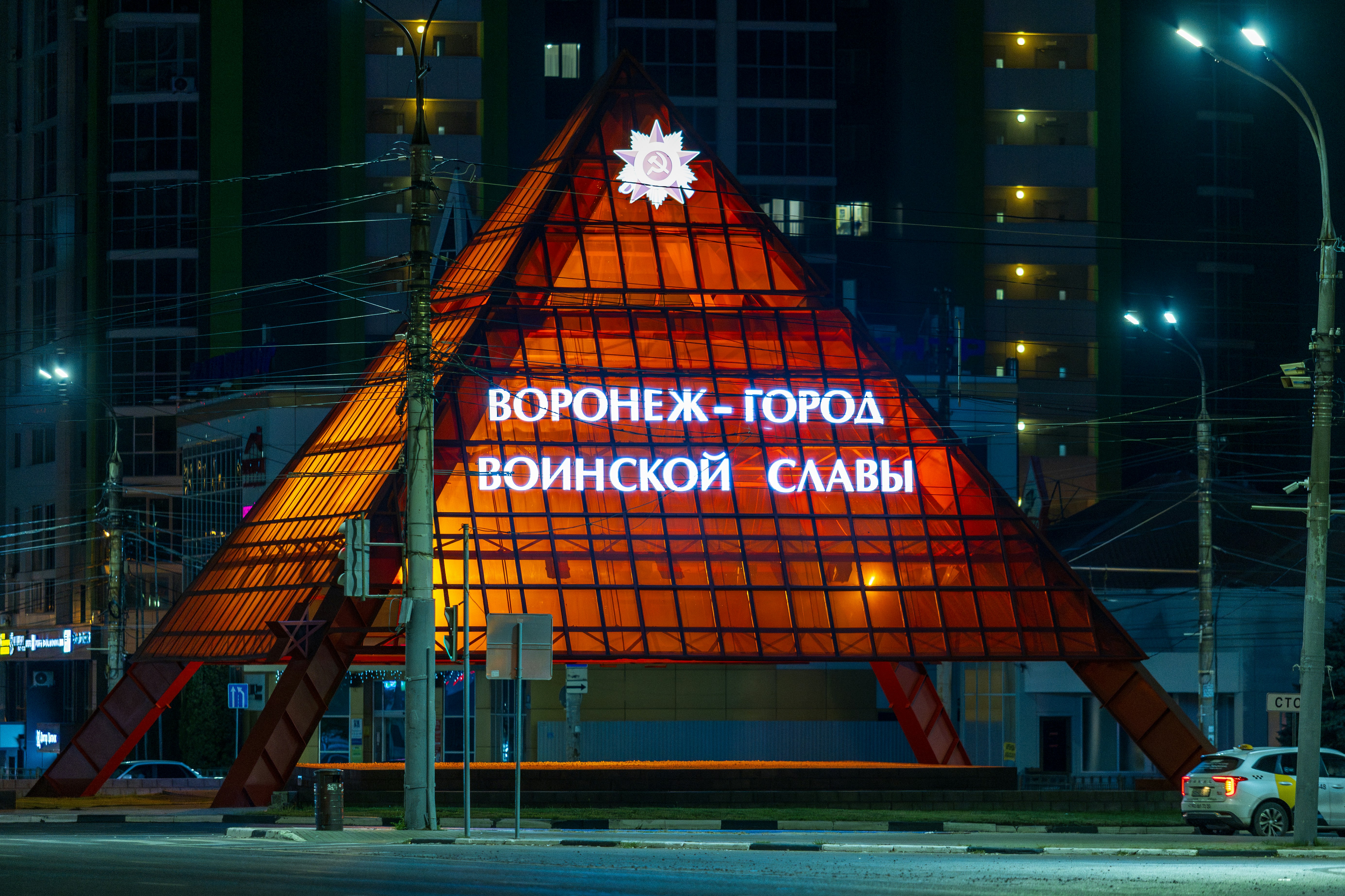 Illuminated pyramid monument at night with russian text
