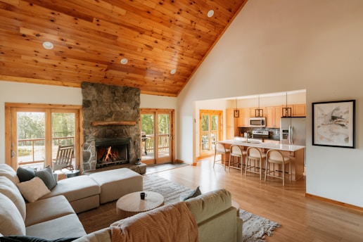 Spacious living room with stone fireplace and open kitchen.