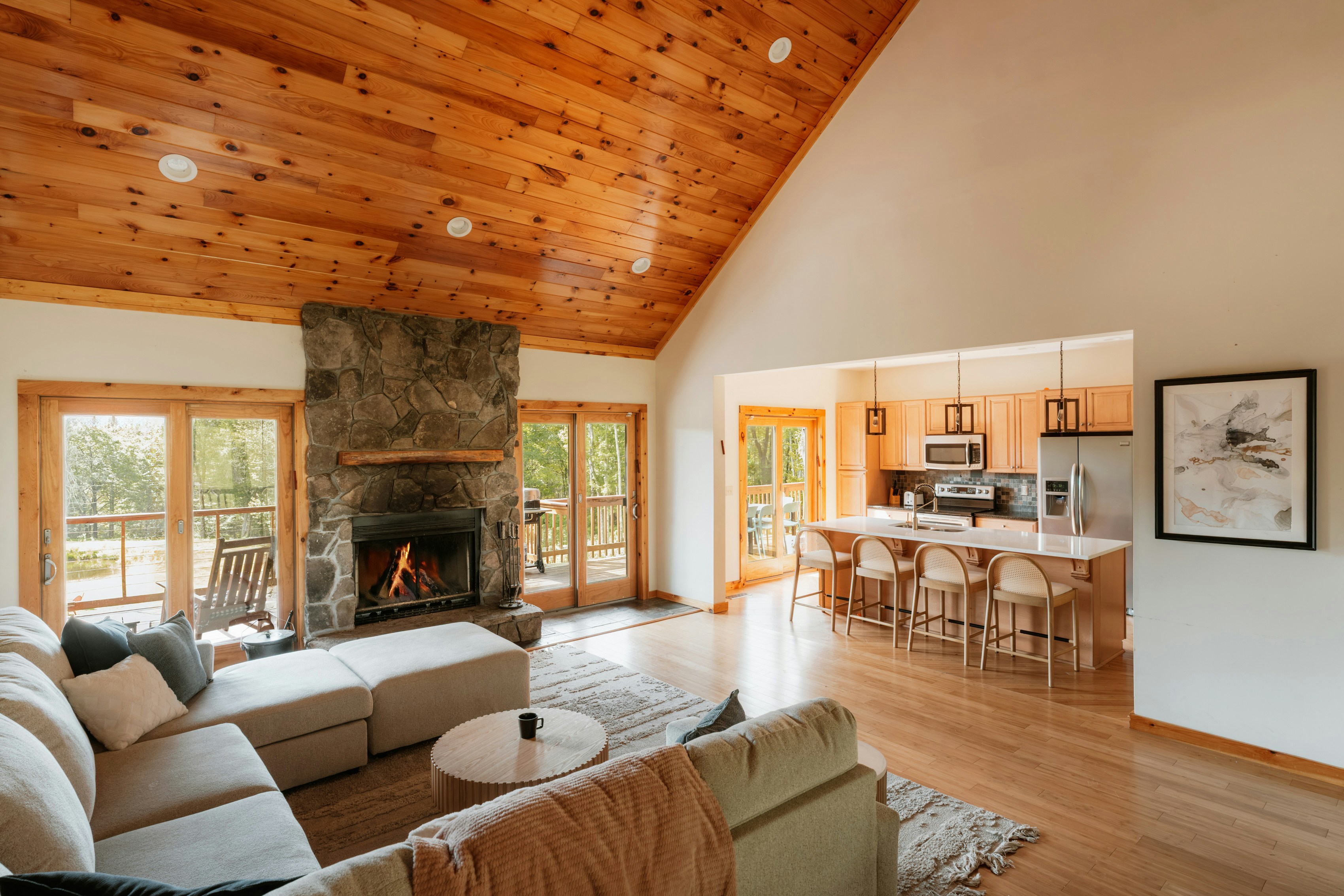 Spacious living room with stone fireplace and open kitchen.