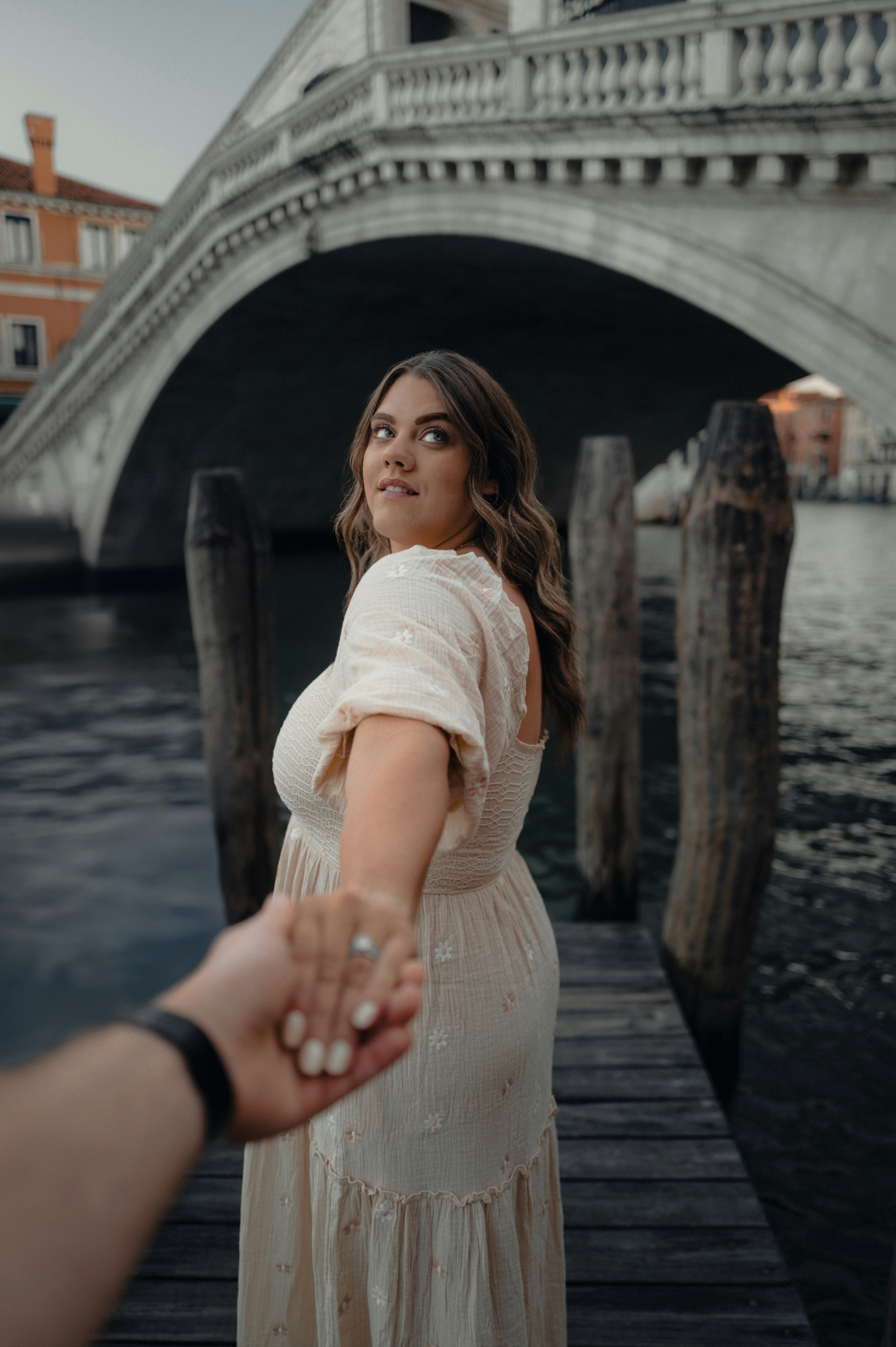 Woman holding hand on wooden dock near bridge