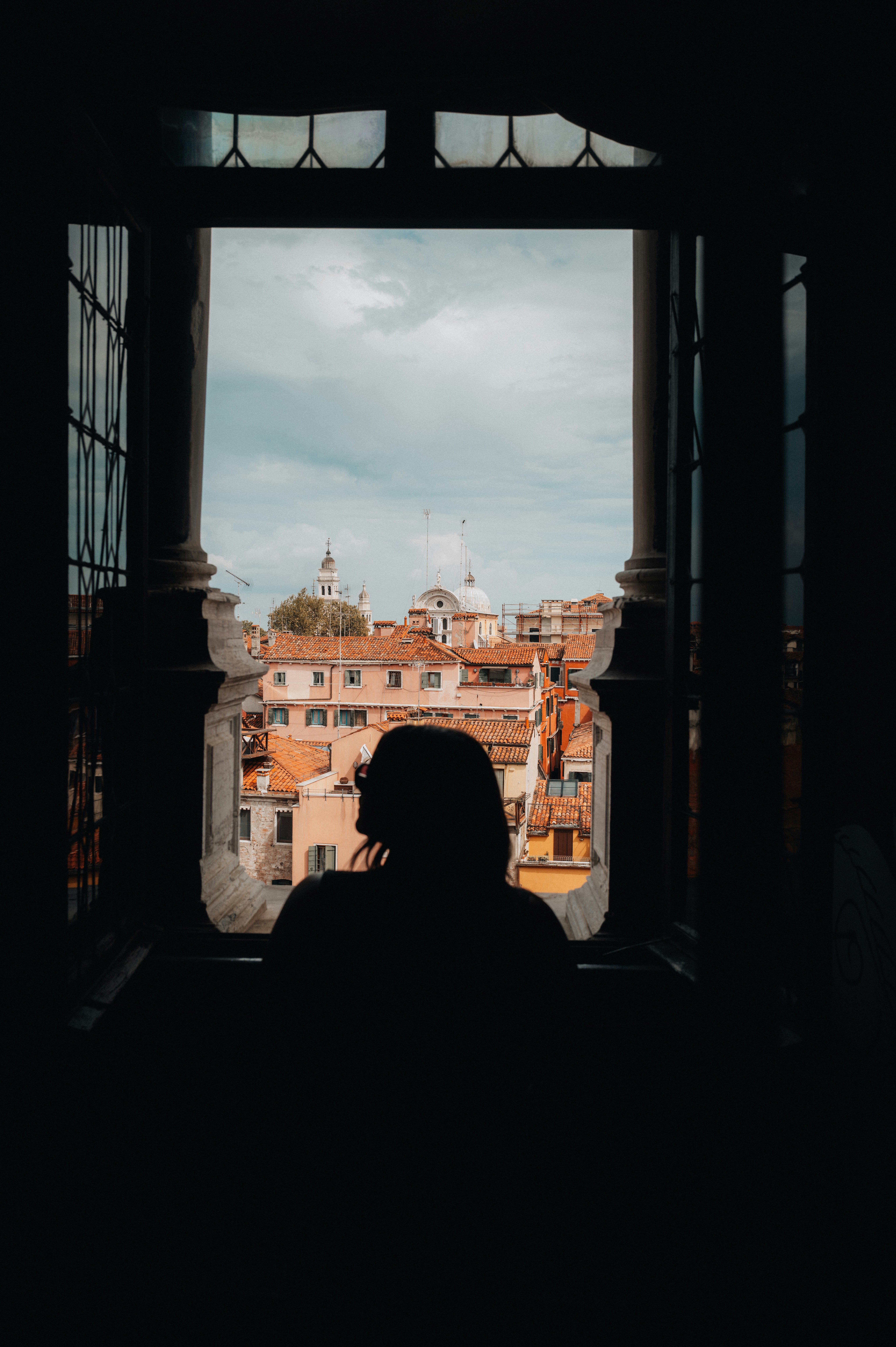 Silhouette of a person looking out window at cityscape