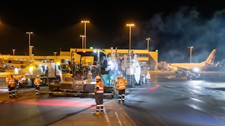 Airport tarmac crew works on asphalt at night.