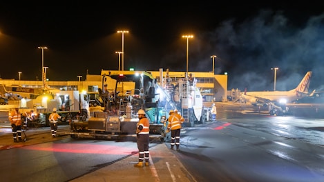 Airport tarmac crew works on asphalt at night.