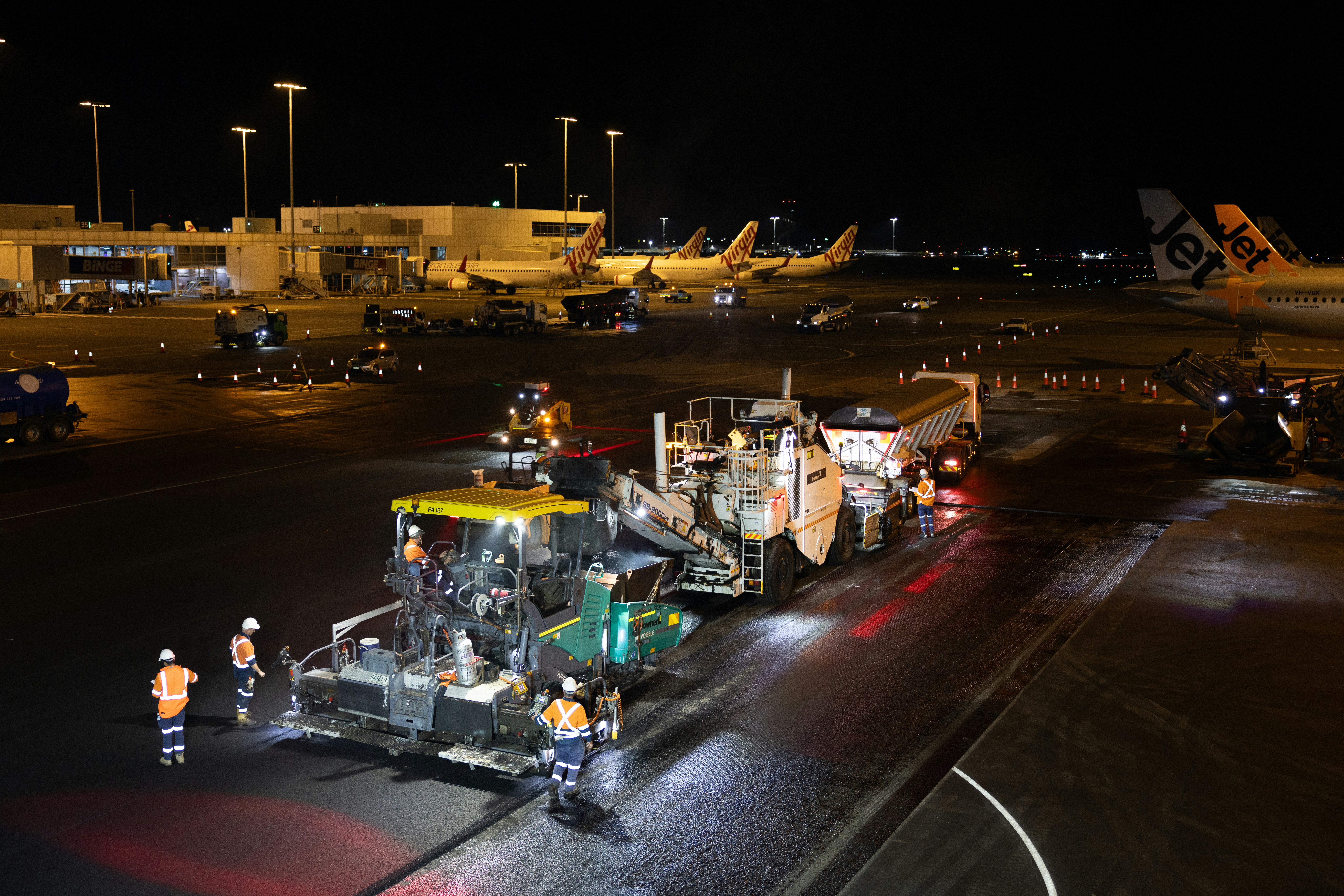Airport tarmac resurfacing work at night with machinery and machinery