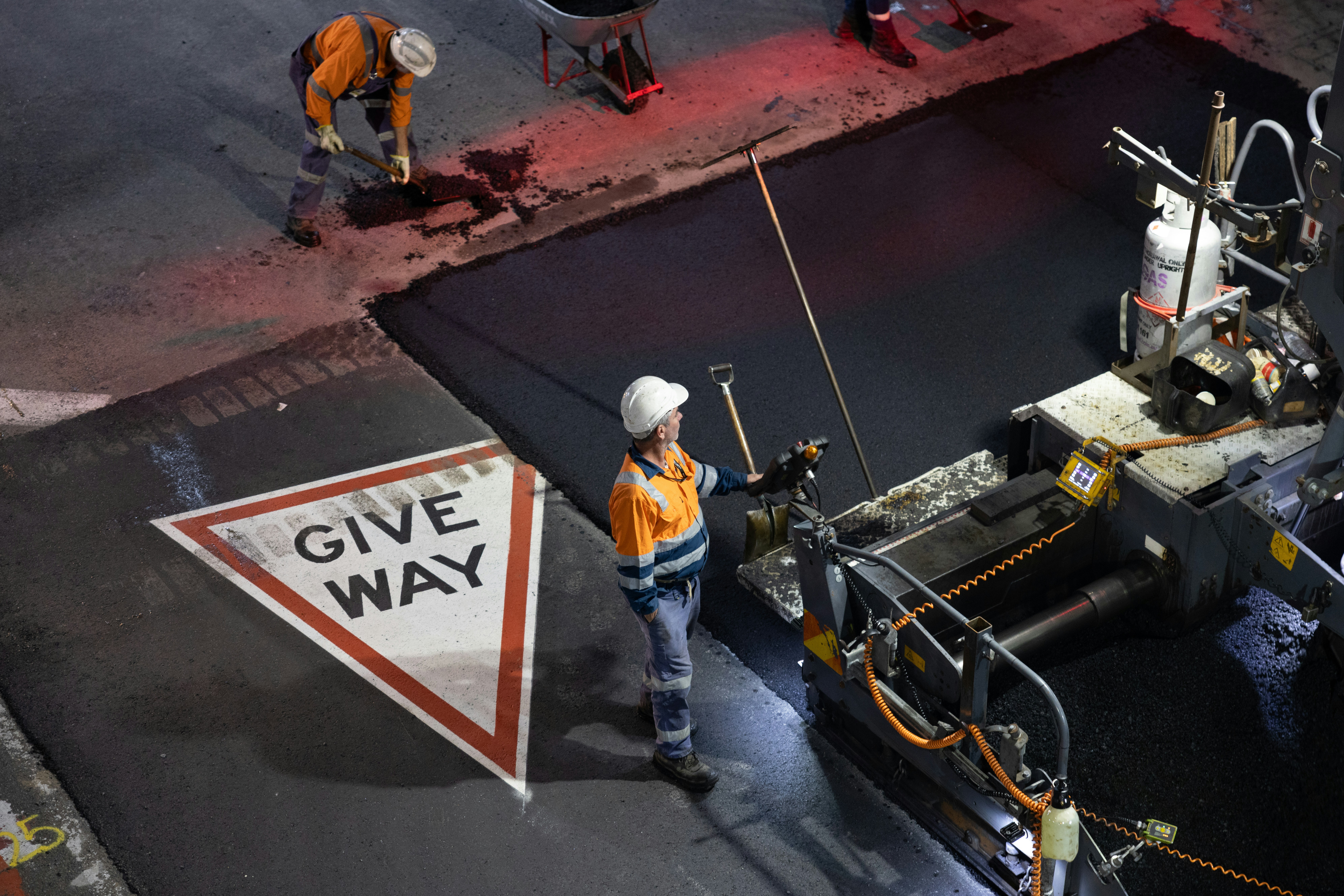 Workers paving a road with asphalt and asphalt machine.