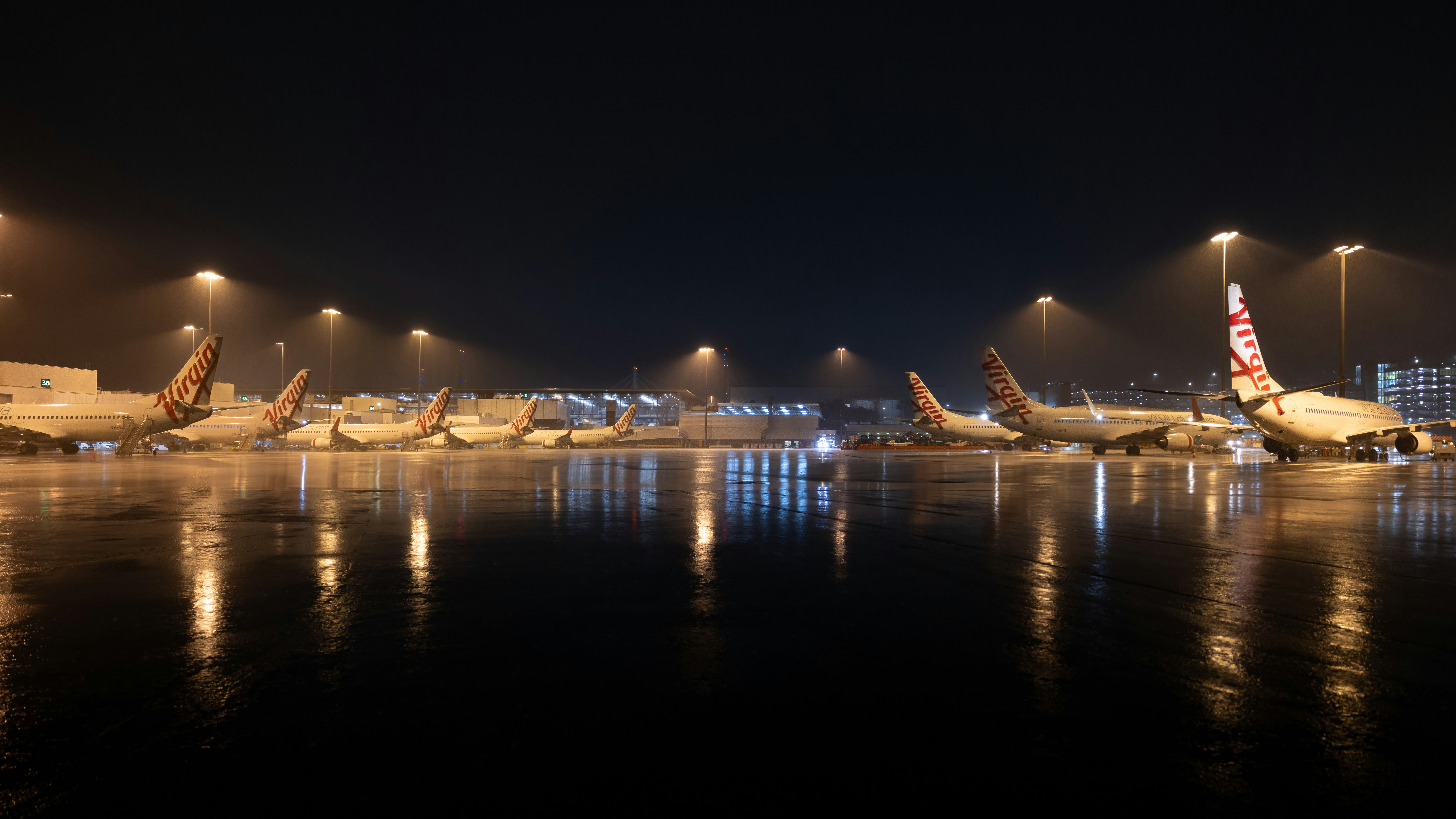 Airplanes parked on wet tarmac at night