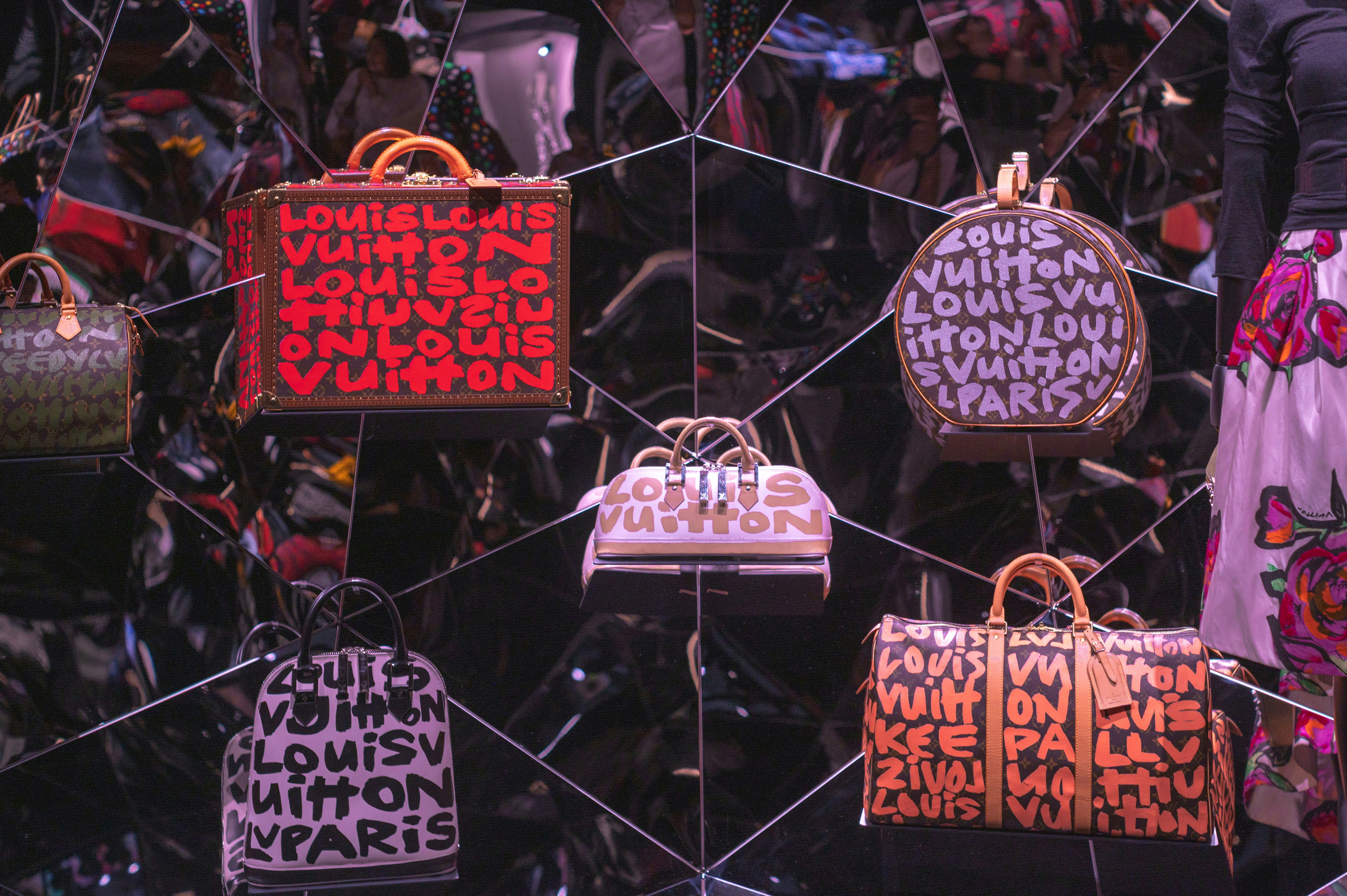 Designer handbags and a trunk displayed on gallery shelves.