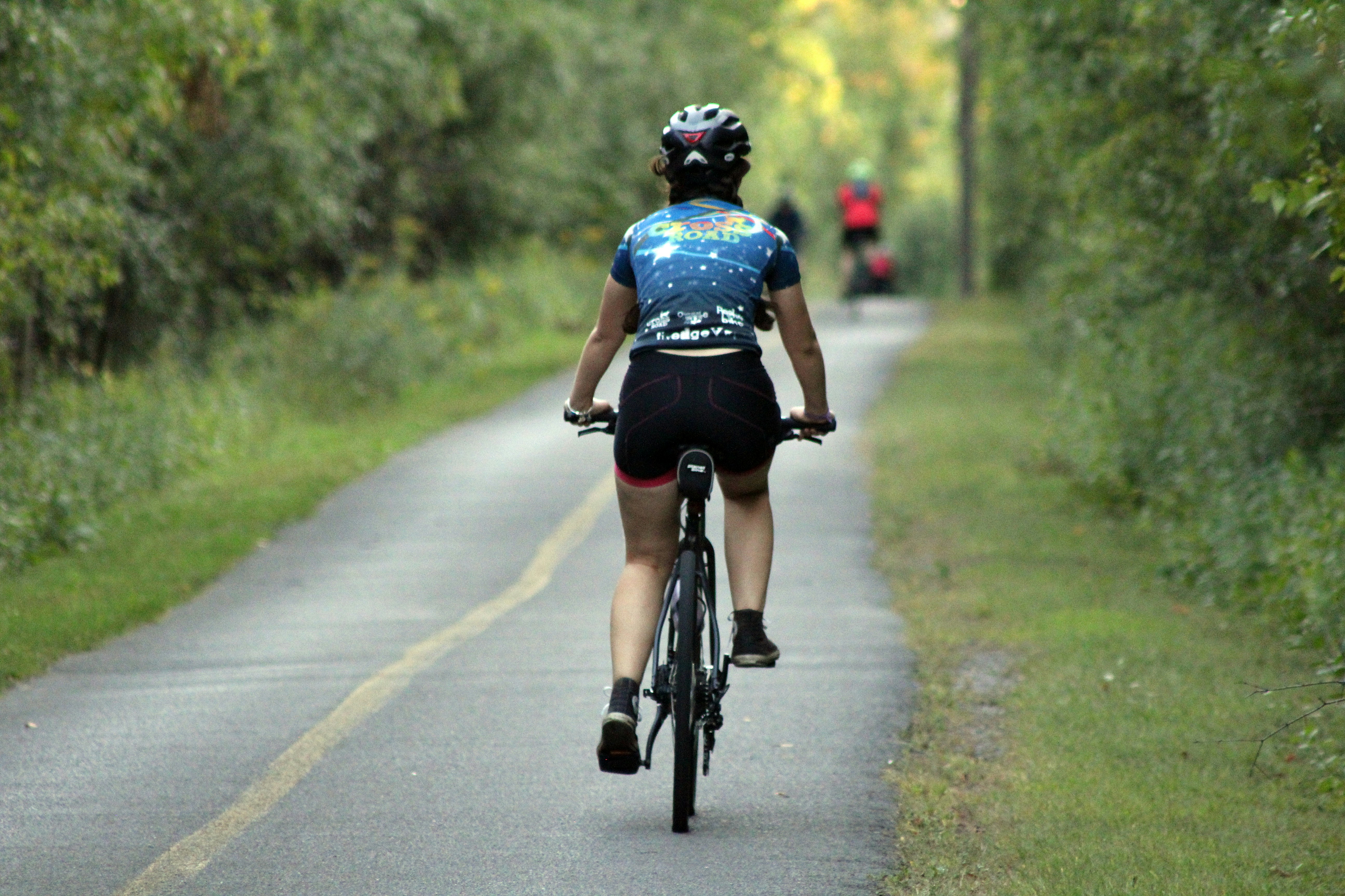 A person rides a bicycle on a paved trail.