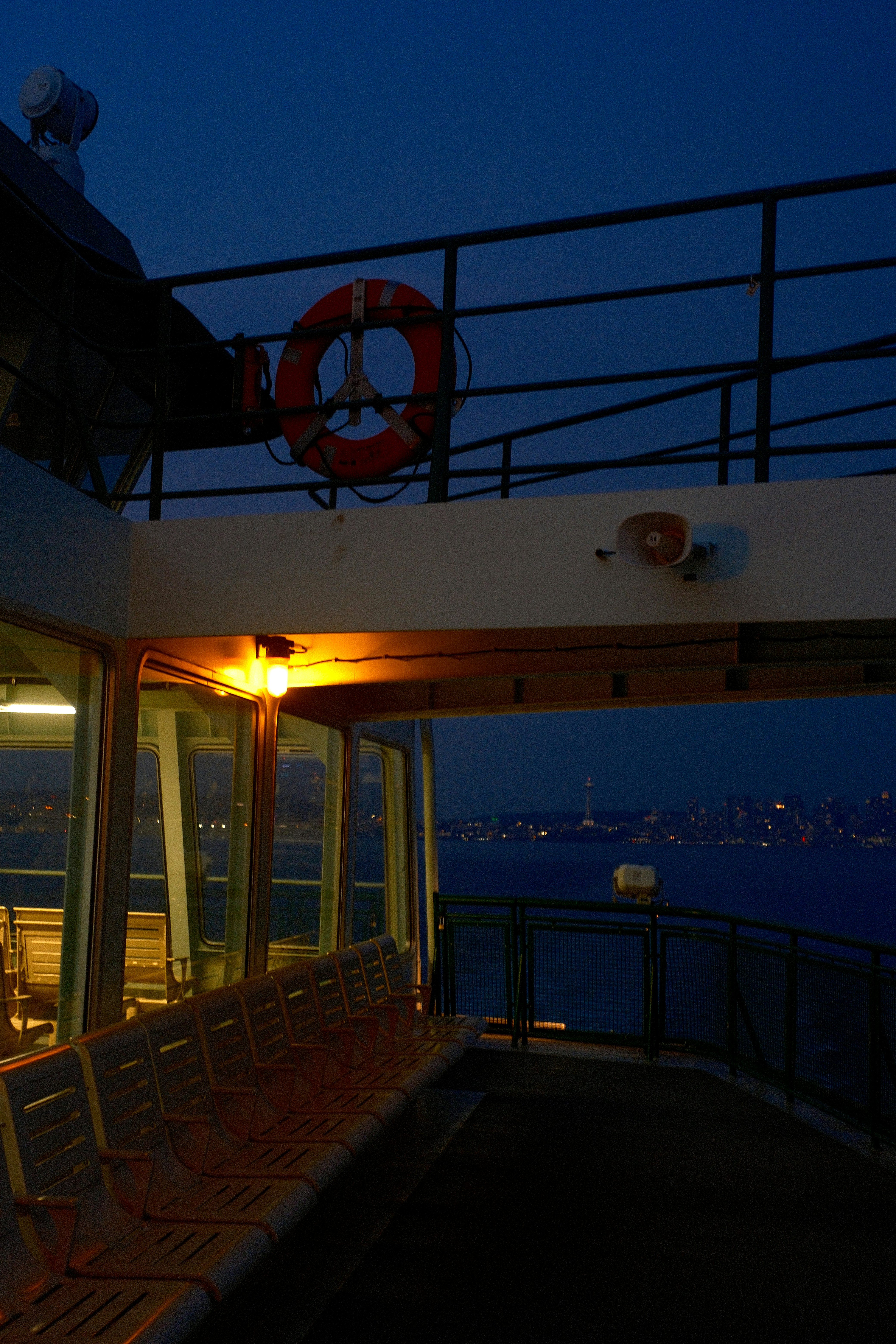 Ferry deck at dusk with city lights across water